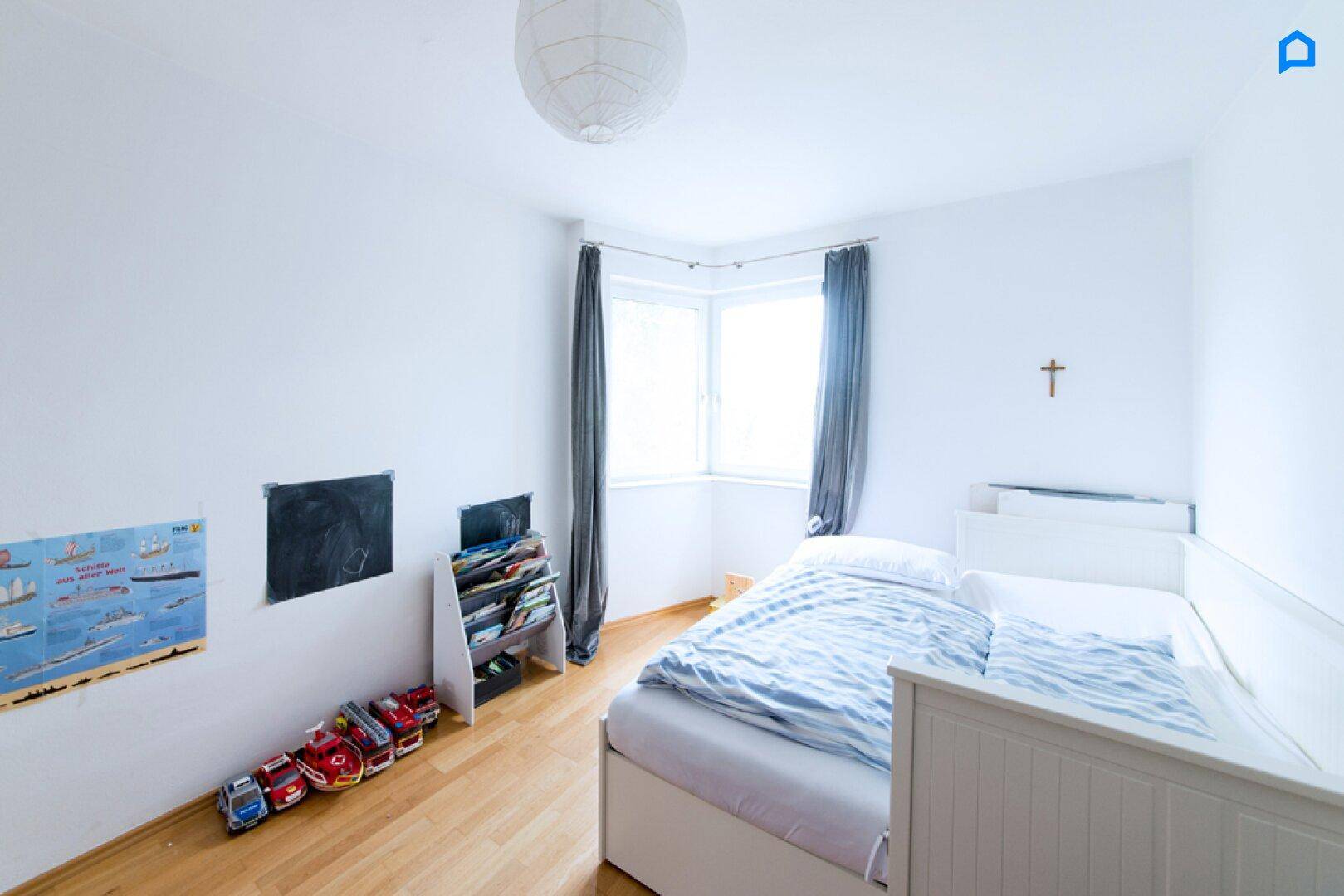 Kinderzimmer mit Einzelbett, Parkettboden und Eckfenster.