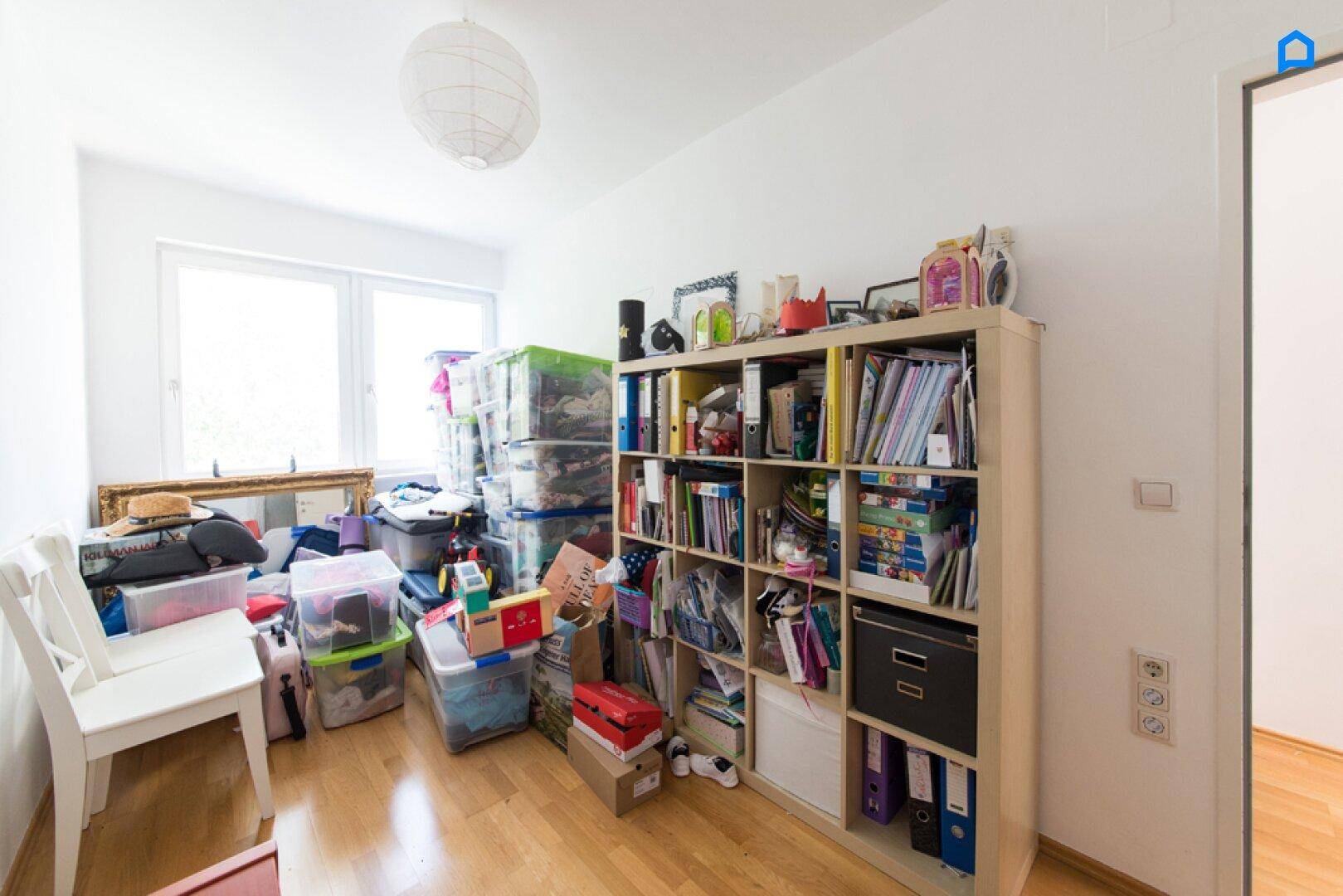 Raum mit Fenster, gefüllt mit Lagerboxen und Regalen.