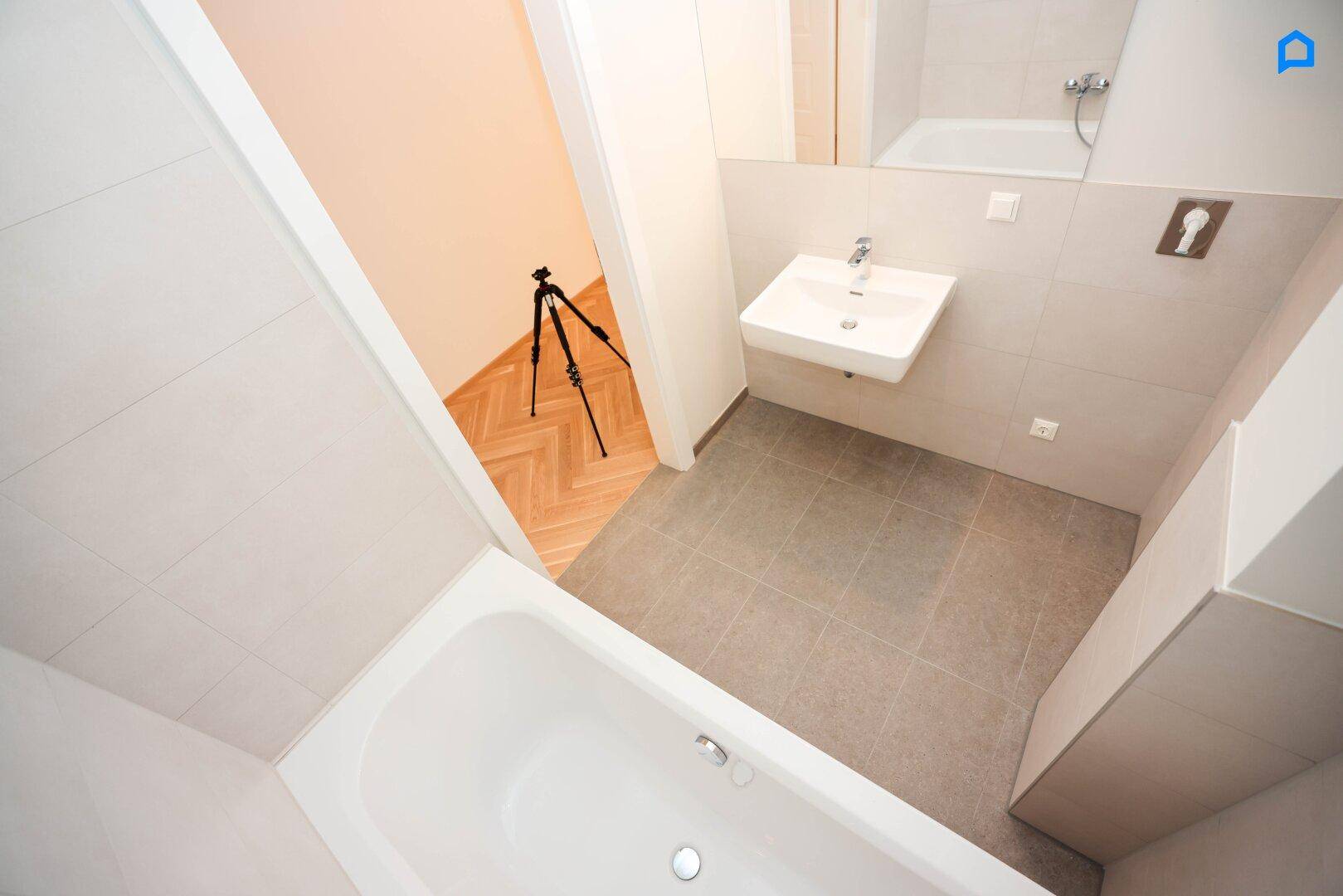 Modernes Badezimmer mit Badewanne, Waschbecken und Blick in angrenzendes Zimmer.