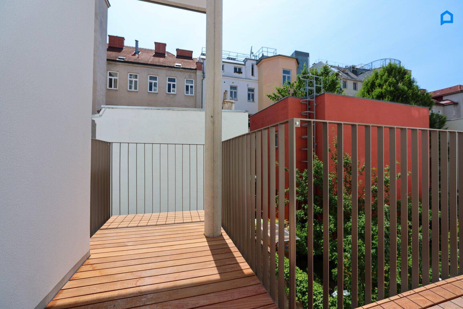 Sonniger Holzbalkon mit modernem Metallgeländer und Blick auf die Stadt.