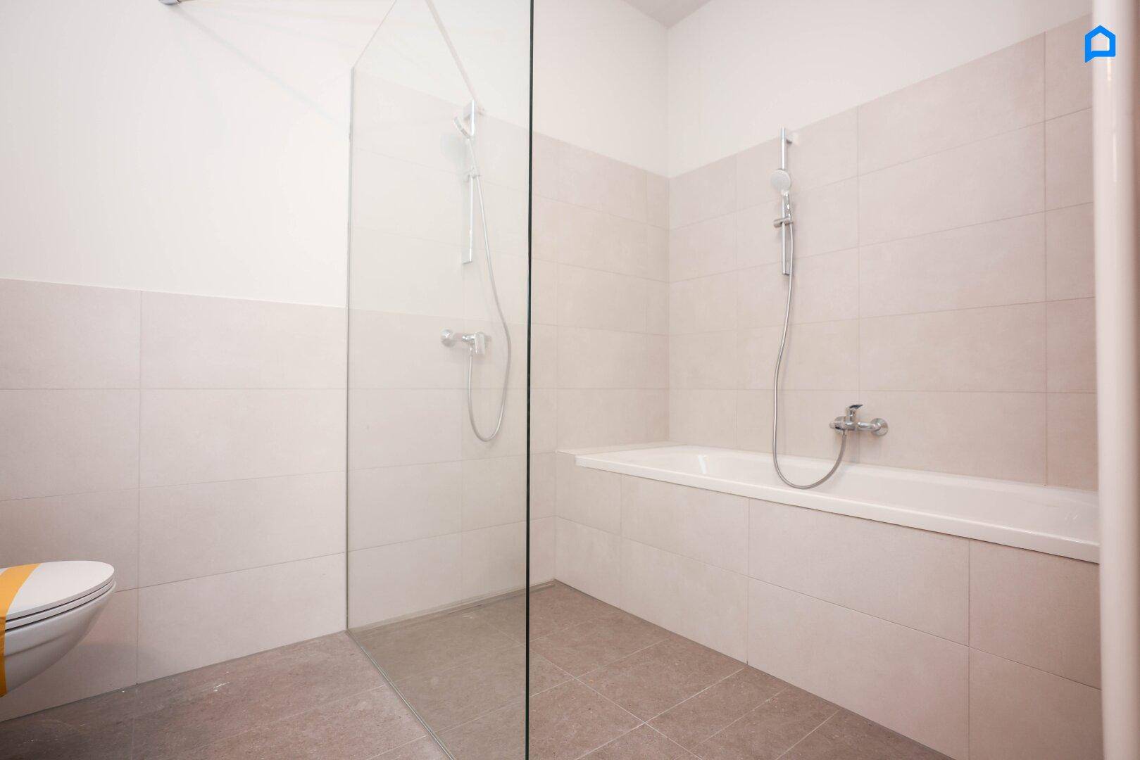 Modernes Badezimmer mit Badewanne und separater Duschkabine aus Glas, hell gefliest.