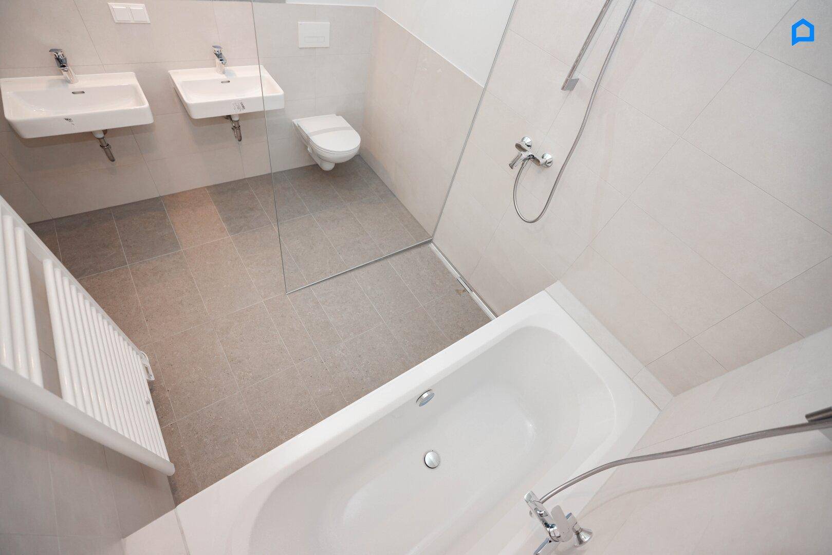 Modernes Badezimmer mit Doppelwaschbecken, Badewanne, Duschbereich und Handtuchheizkörper.
