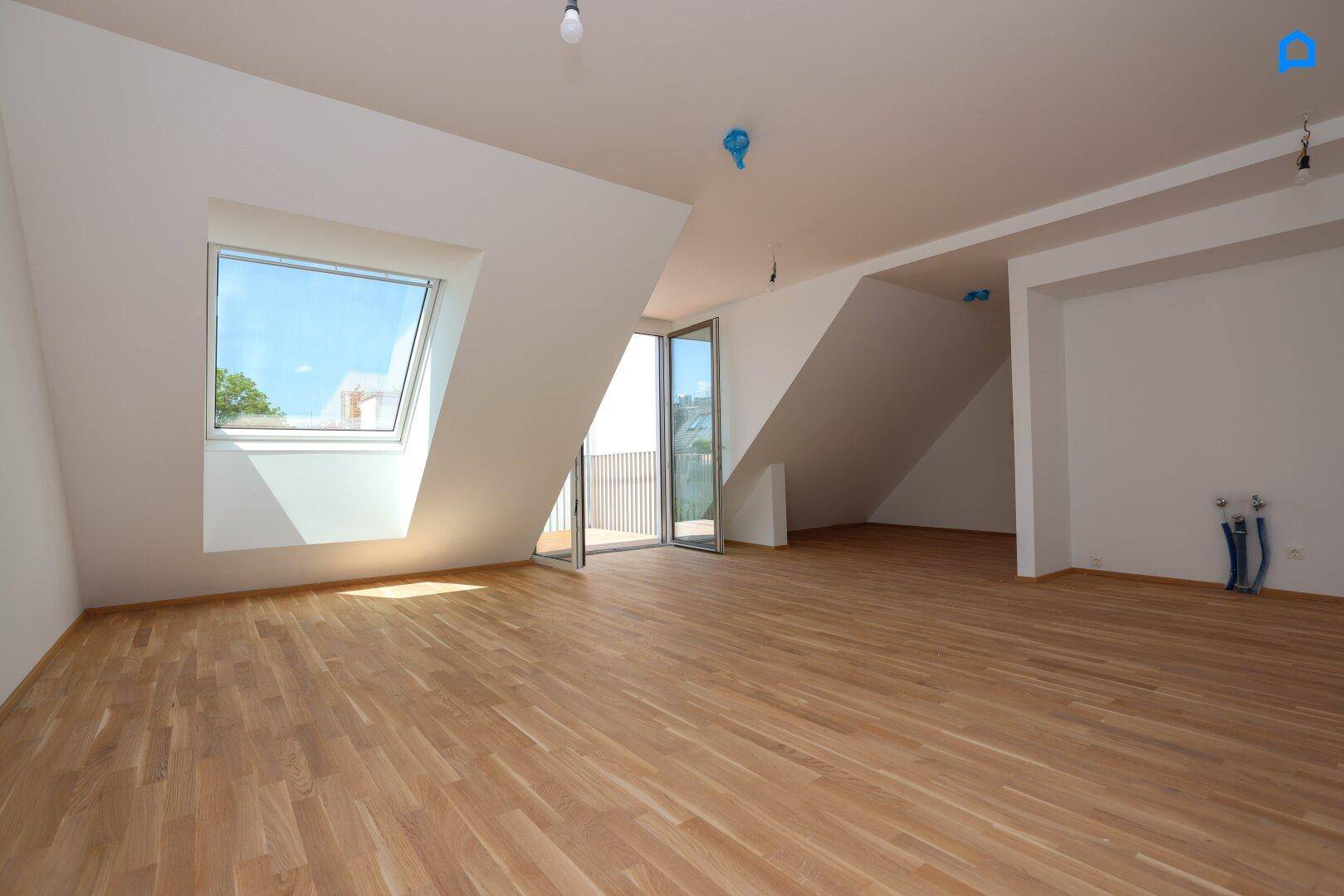 Geräumiges Dachgeschosszimmer mit Holzboden, Dachfenster und Zugang zum Balkon, sehr hell.