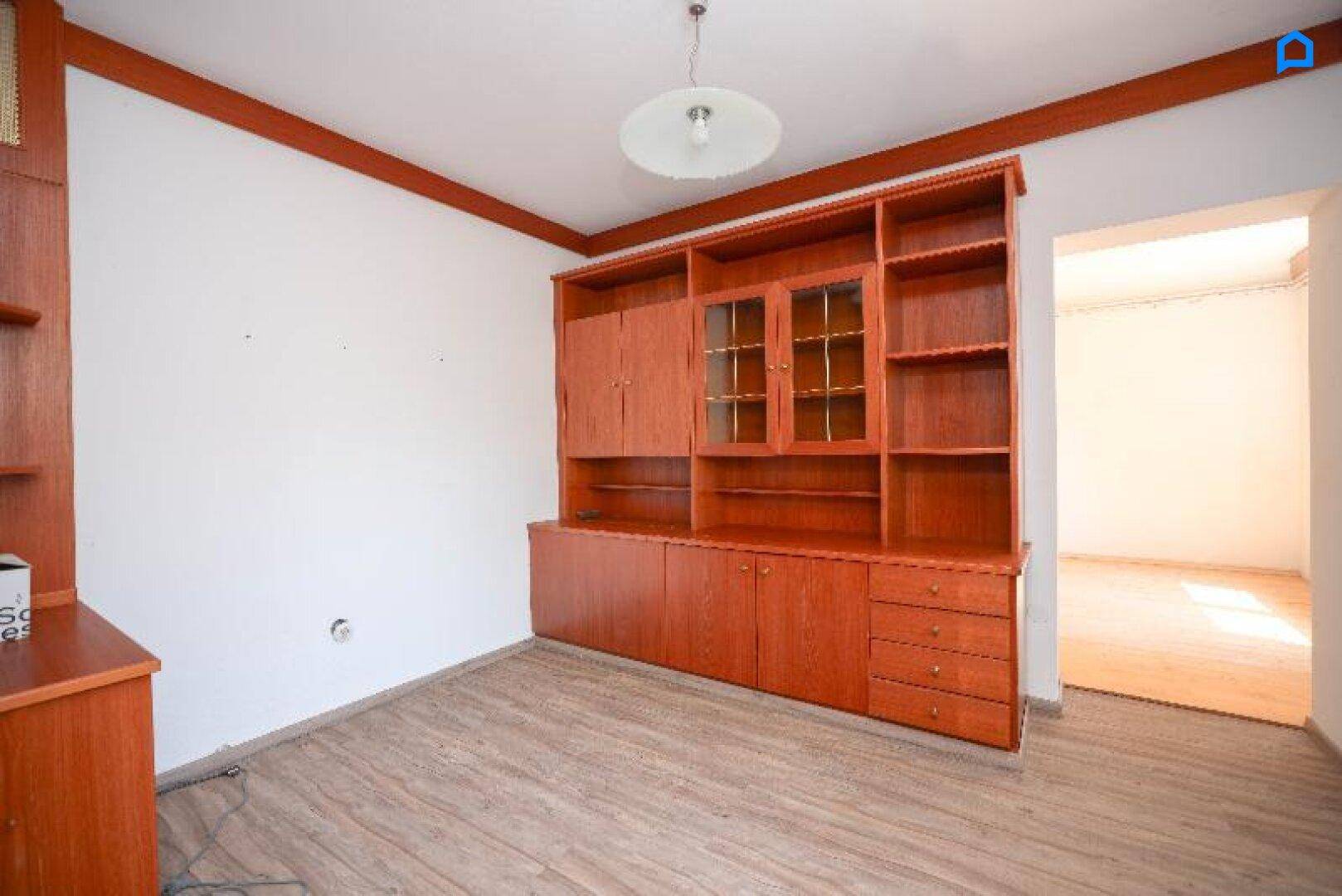 Geräumiges Zimmer mit Holzschrankwand und Laminatboden, bereit zur individuellen Gestaltung.