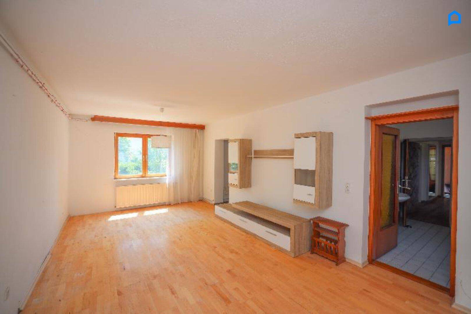 Helles Wohnzimmer mit Holzboden, Fenster und modernen Wandregalen.