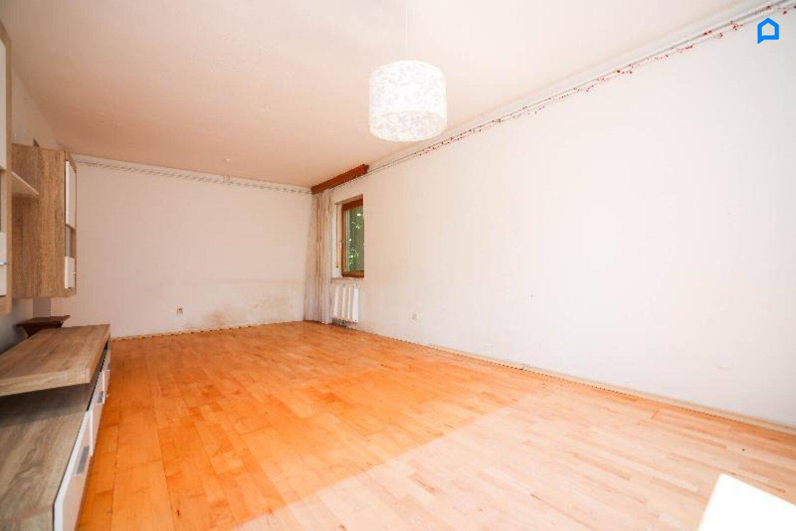 Helles Wohnzimmer mit Holzboden und Fenster, bietet viel Platz für individuelle Einrichtung.
