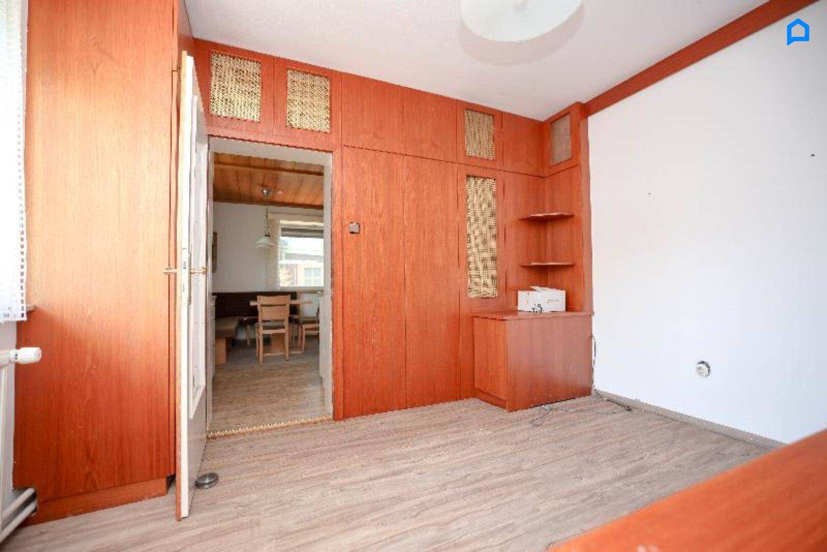 Zimmer mit Holzvertäfelung und Laminatboden, bietet Zugang zur Küche.