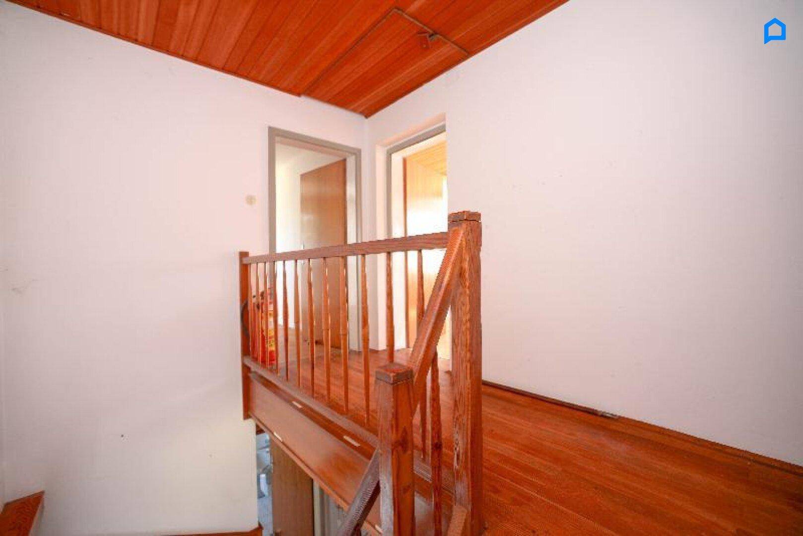 Heller Flur im Obergeschoss mit Holzgeländer und Holzboden.