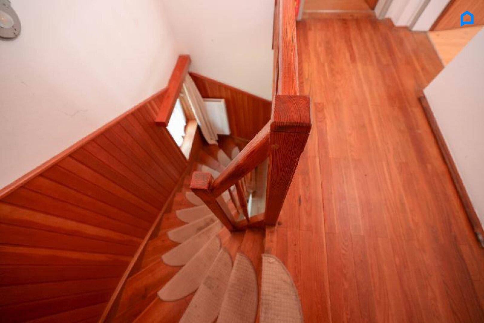 Blick von oben auf die Holztreppe mit Teppichläufern und Holzvertäfelung.