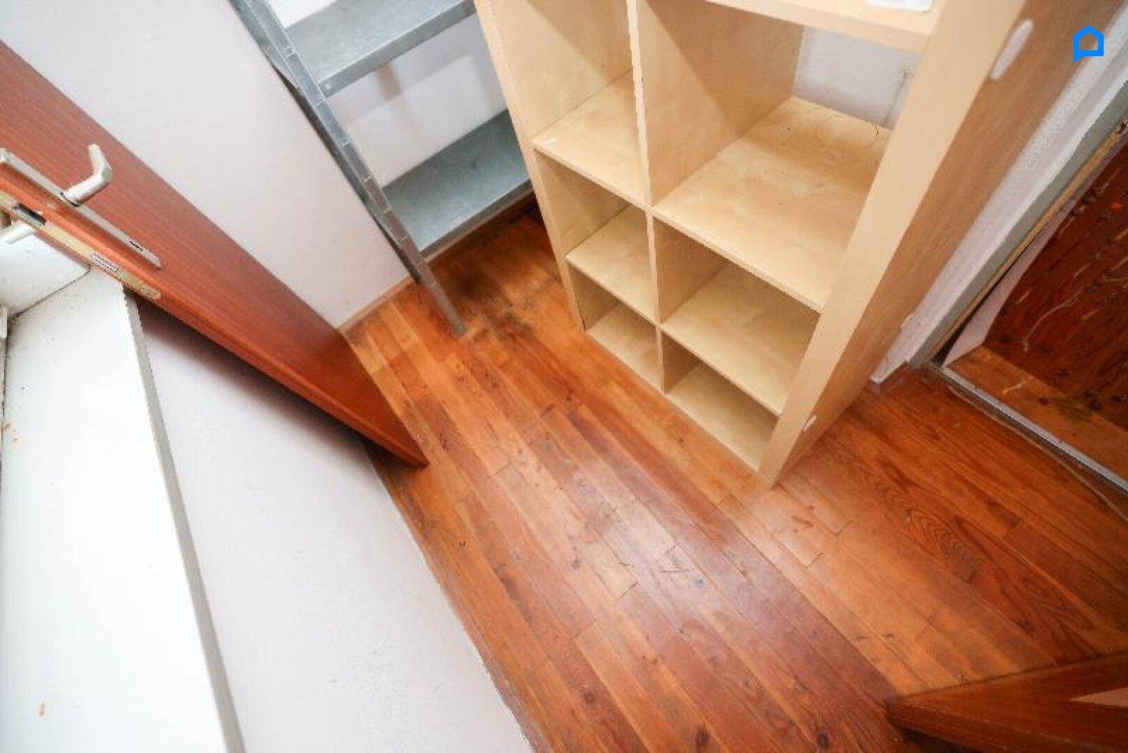 Kleiner Abstellraum mit Holzregal und Holzboden, ideal für zusätzlichen Stauraum.