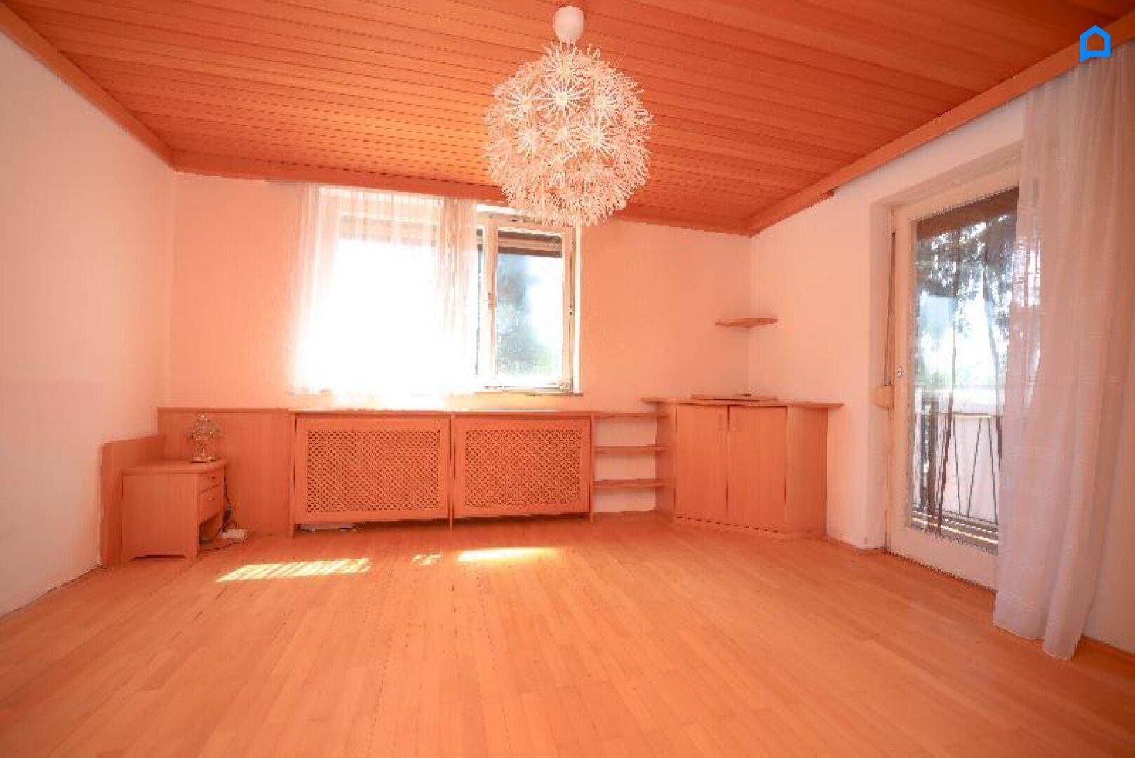 Helles Schlafzimmer mit Holzboden, Holzdecke und Zugang zum Balkon.
