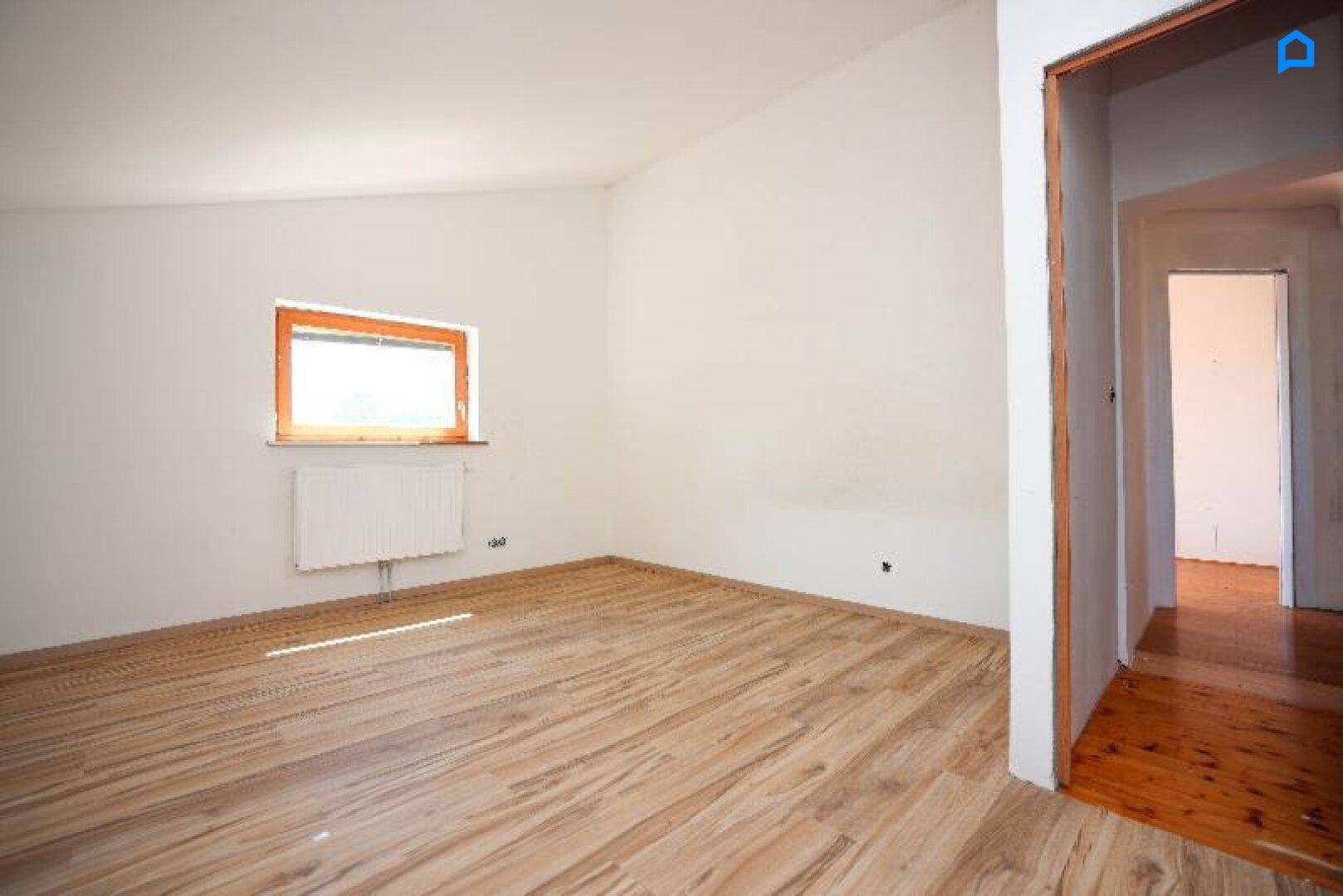Geräumiges Schlafzimmer mit Laminatboden und Fenster, das viel Tageslicht hereinlässt.