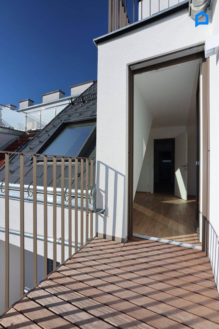 Kleiner Balkon mit Holzboden und Blick auf die Dächer, zugänglich vom Innenraum.