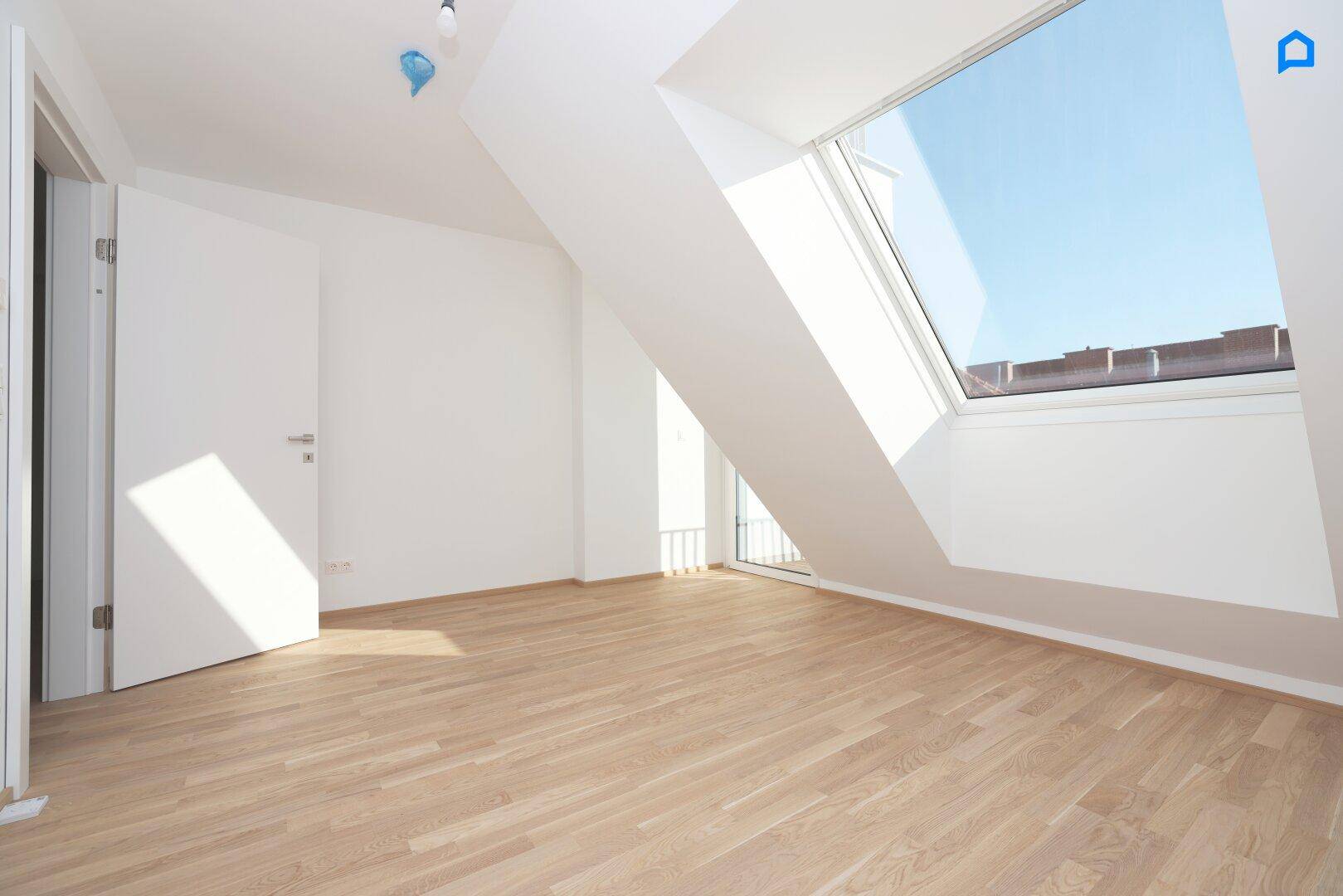 Lichtdurchflutetes Dachgeschosszimmer mit Holzboden und großem Dachfenster, ideal als Schlafzimmer.