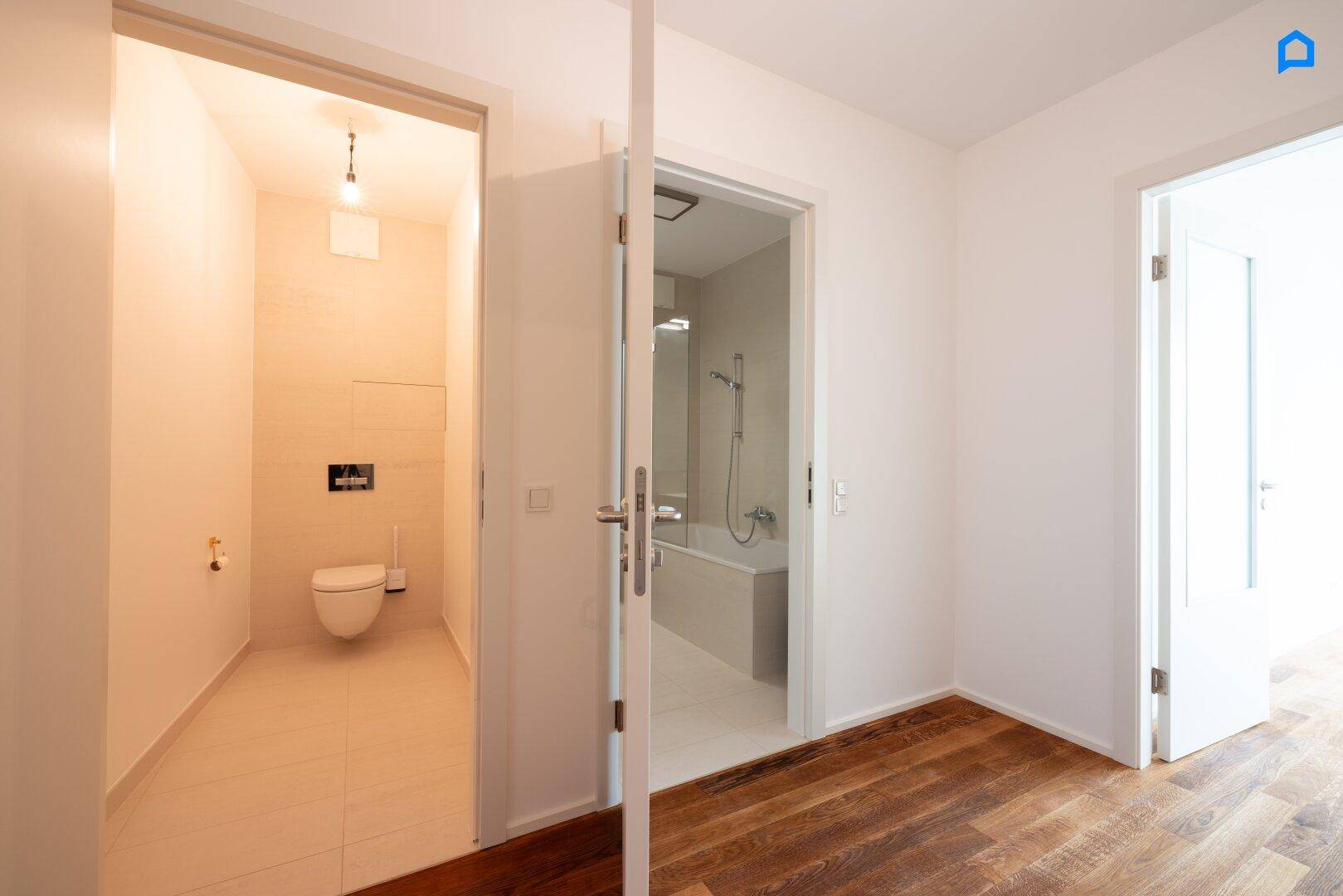 Heller Flur mit Holzboden, der Zugang zu Badezimmer und separatem WC bietet.