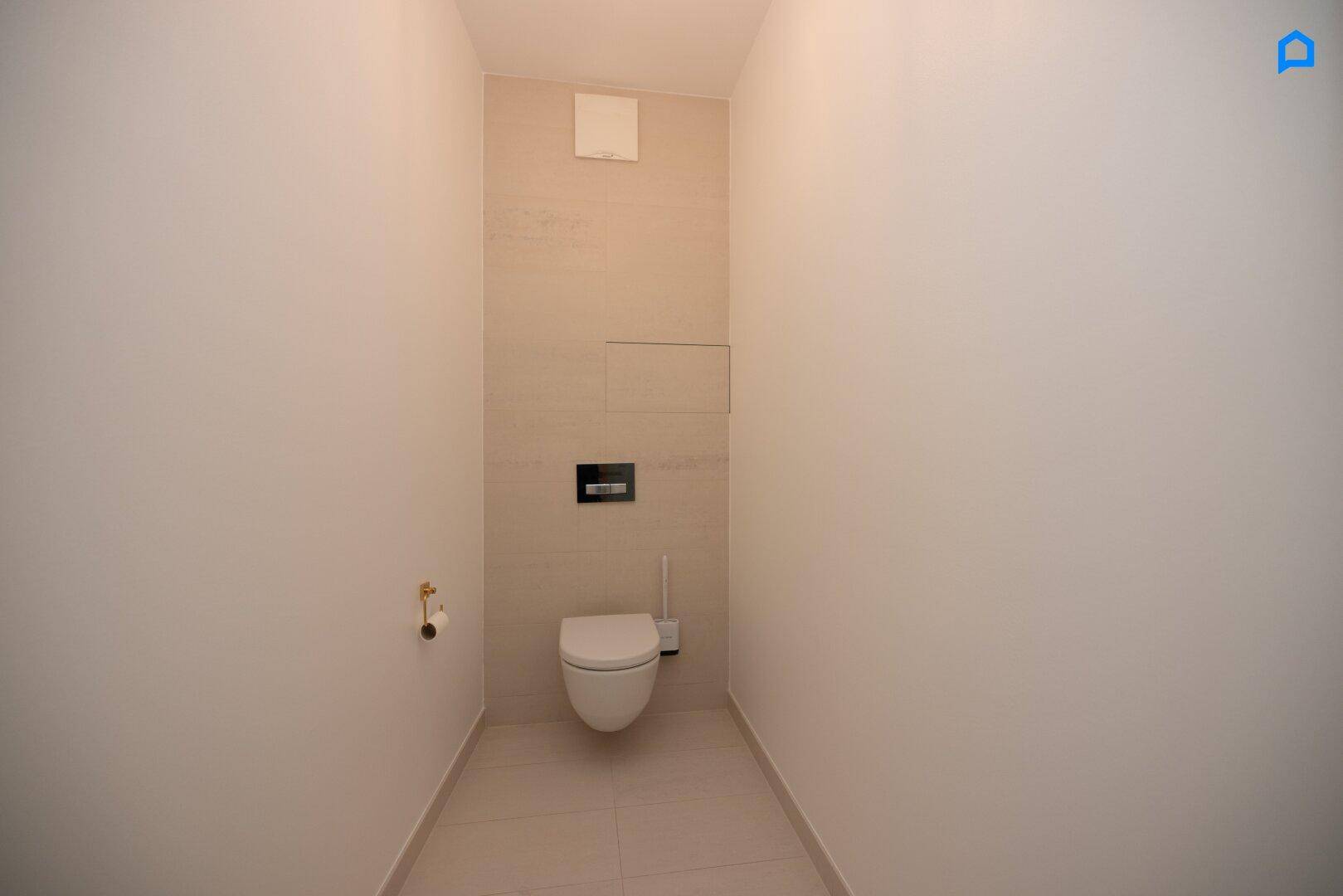 Separates WC mit wandhängender Toilette und hellen Fliesen, minimalistisch gestaltet.