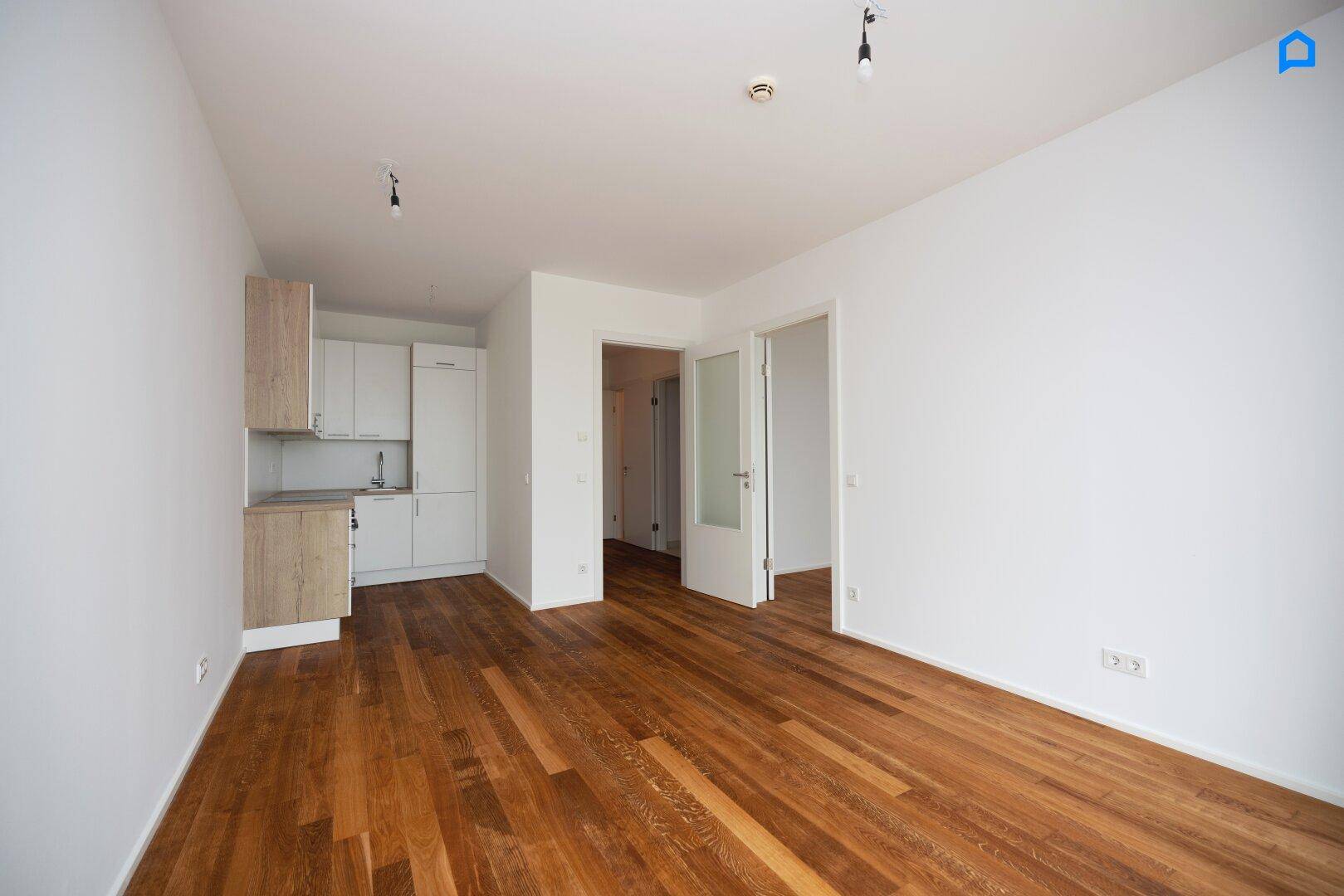 Offener Wohnbereich mit integrierter Küchenzeile und Holzboden, ideal für modernes Wohnen.