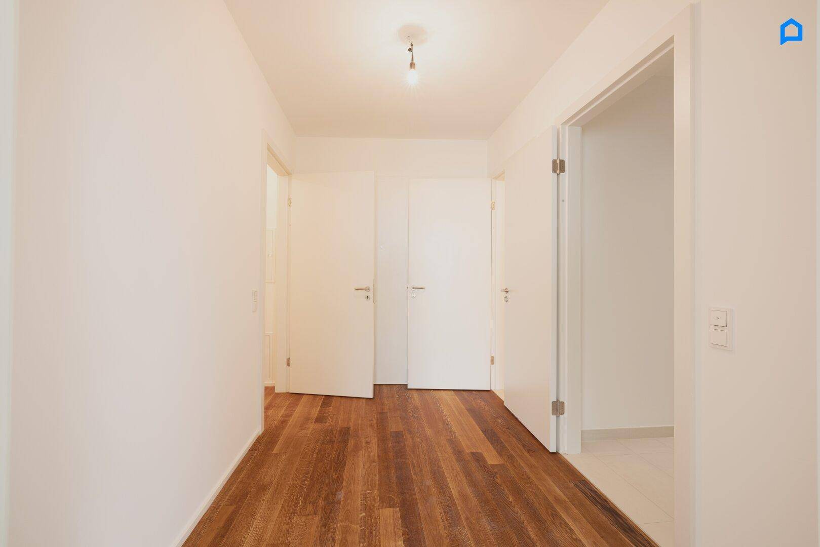 Geräumiger Flur mit Holzboden und mehreren Türen, die zu verschiedenen Räumen führen.