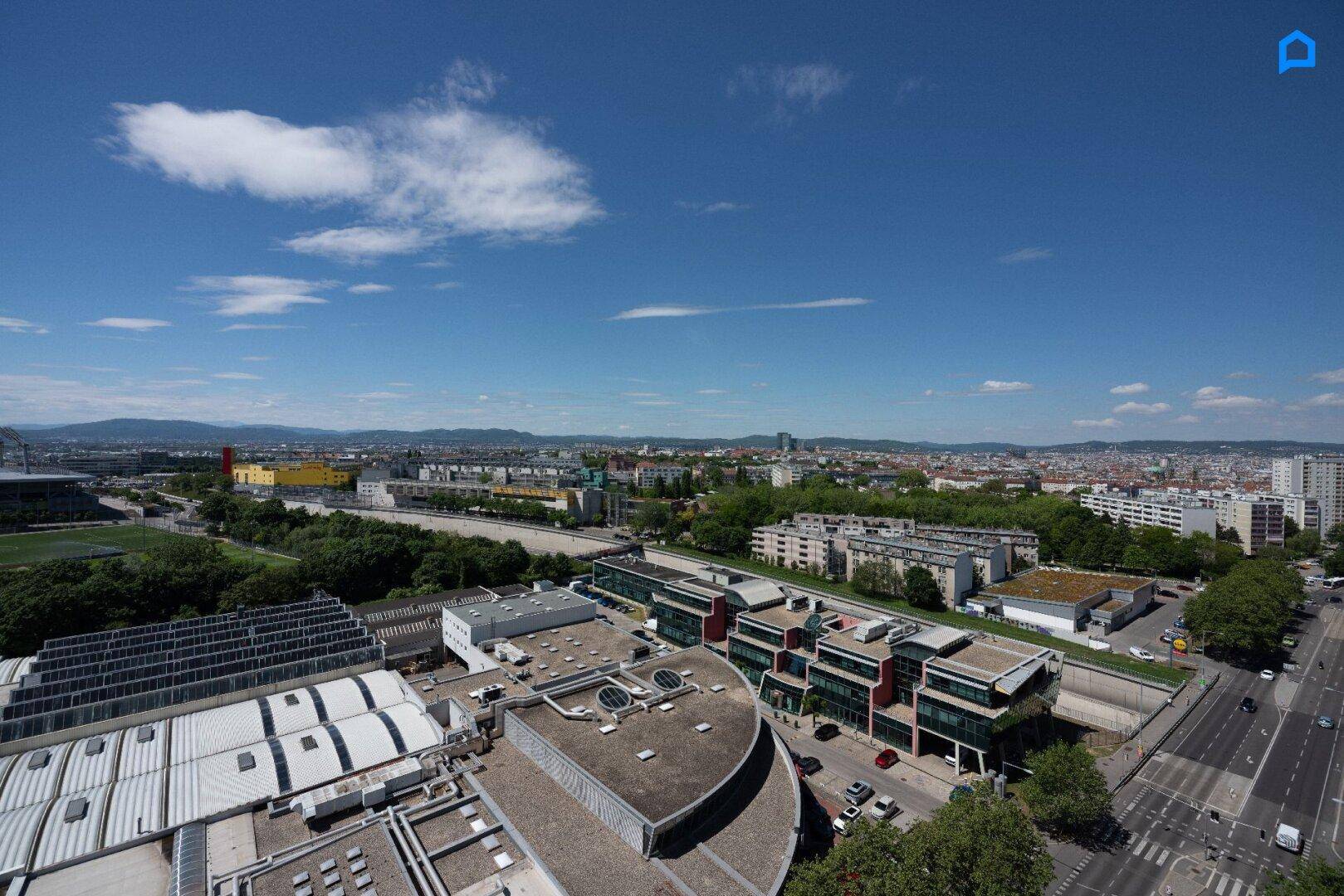 Ausblick auf die städtische Umgebung mit verschiedenen Gebäuden und einer weiten Landschaft.