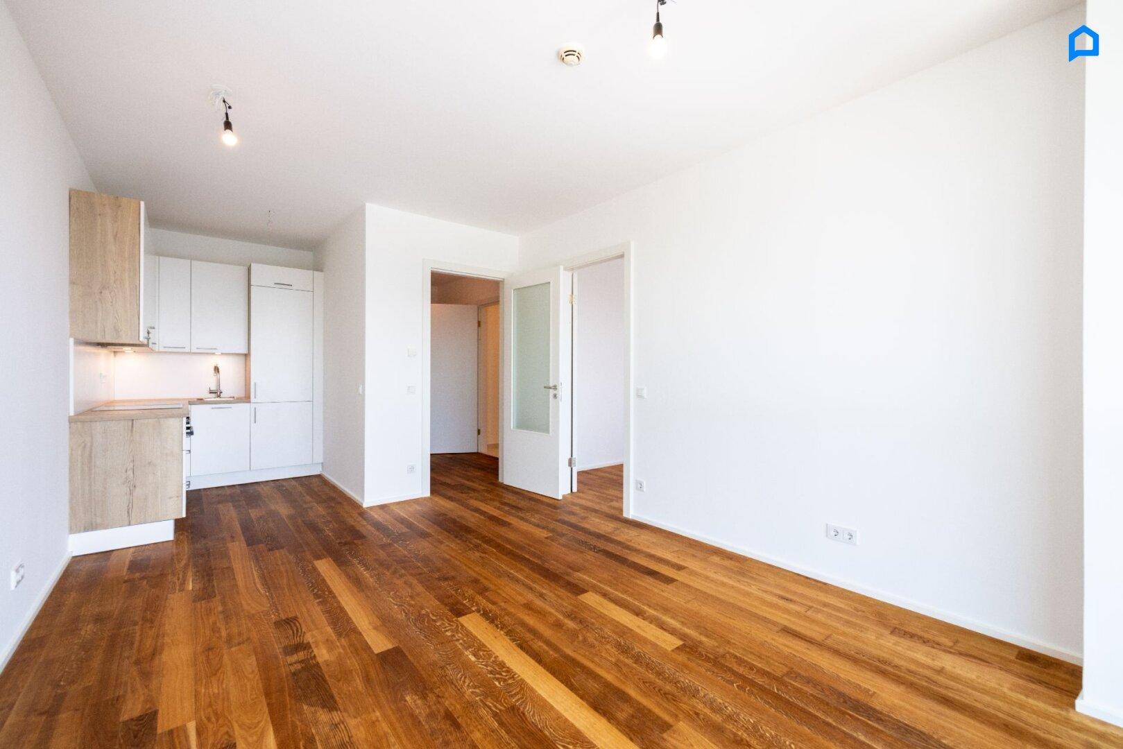 Offener Wohnbereich mit integrierter Küchenzeile und Holzboden, ideal für modernes Wohnen.