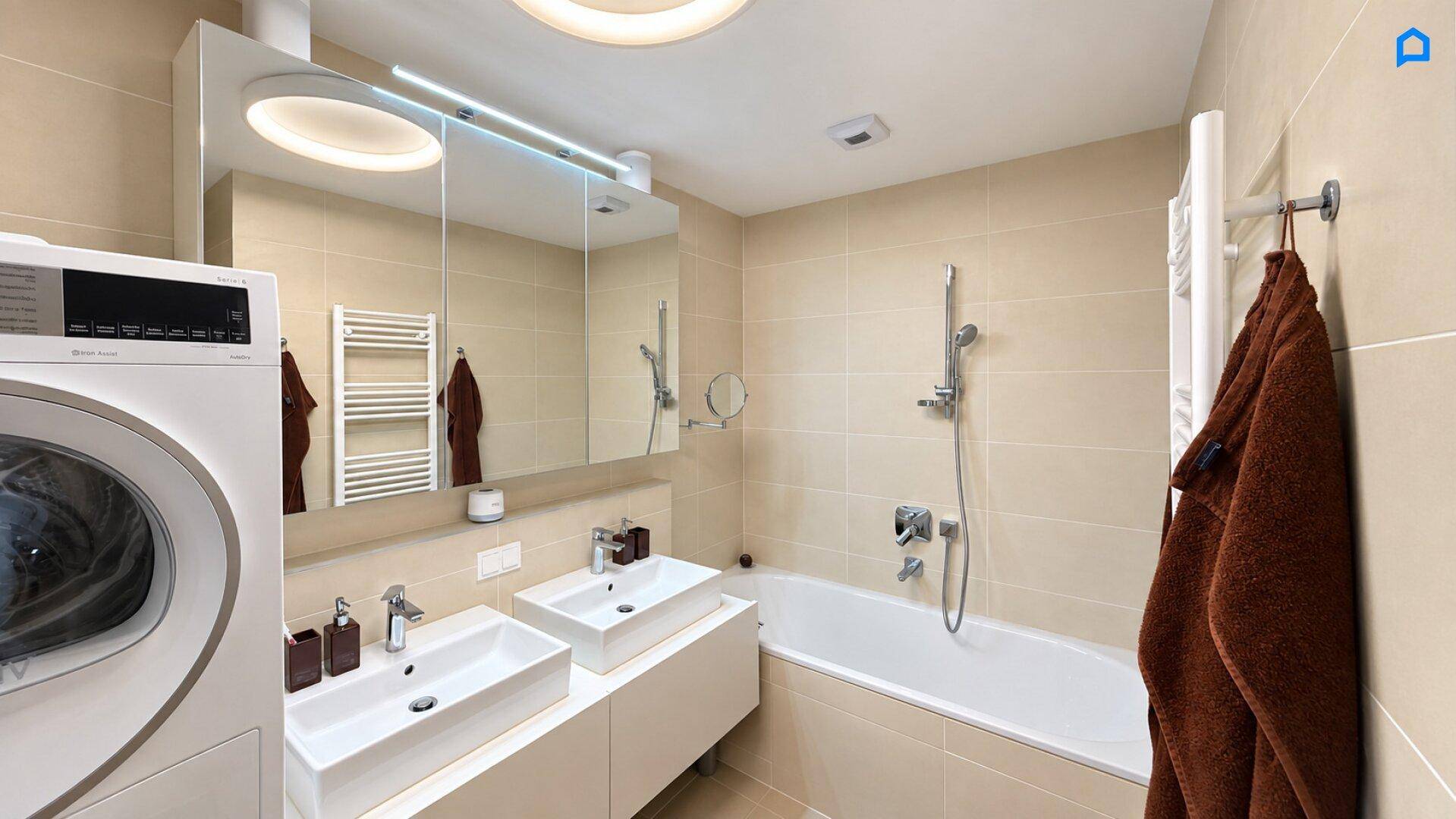 Helles Badezimmer mit Doppelwaschbecken, Badewanne, Waschmaschine und Trockner in modernem Design.