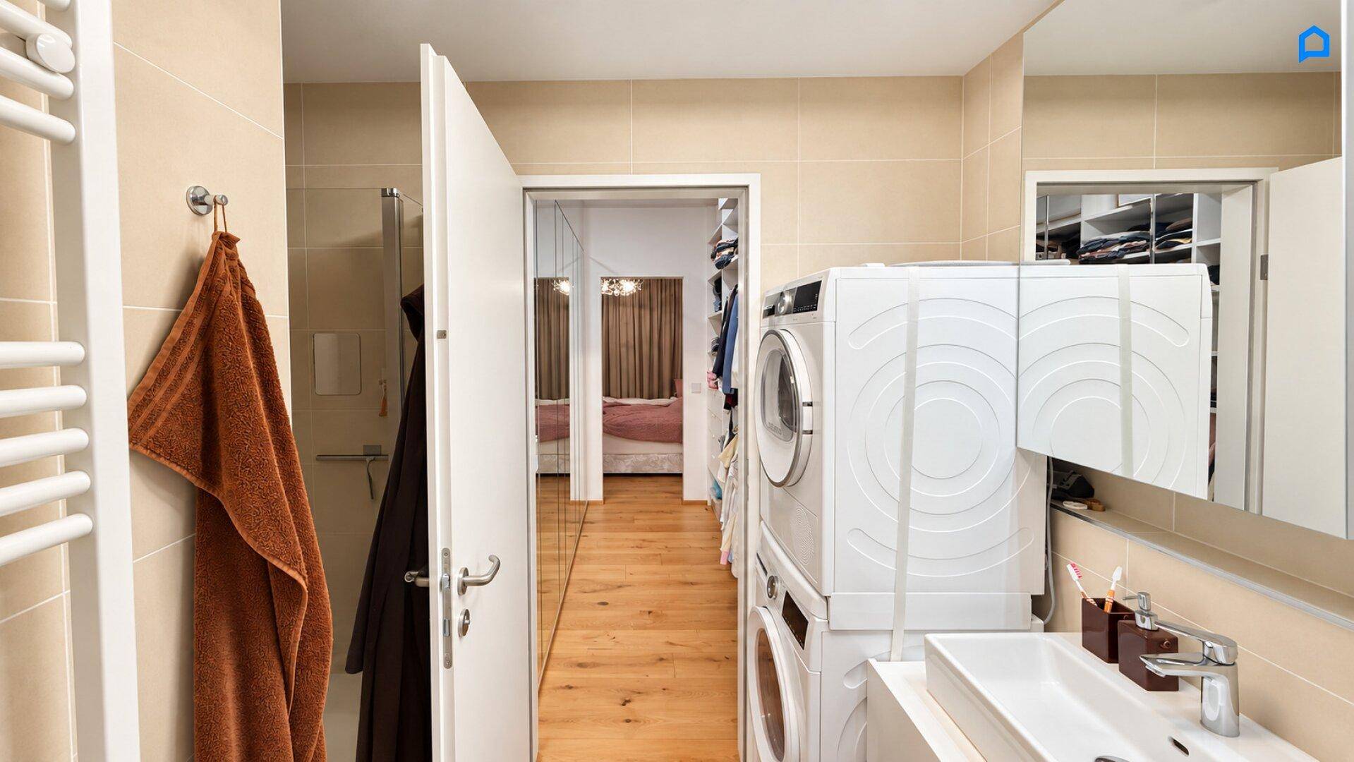 Modernes Badezimmer mit Dusche, Waschmaschine und Trockner, mit Blick auf den begehbaren Kleiderschrank.