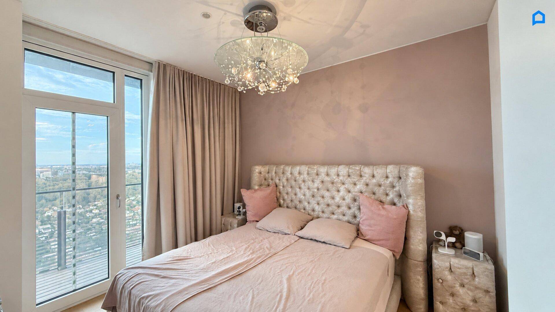 Elegantes Schlafzimmer mit großem Bett, Kronleuchter und weitem Ausblick auf die Stadtlandschaft.