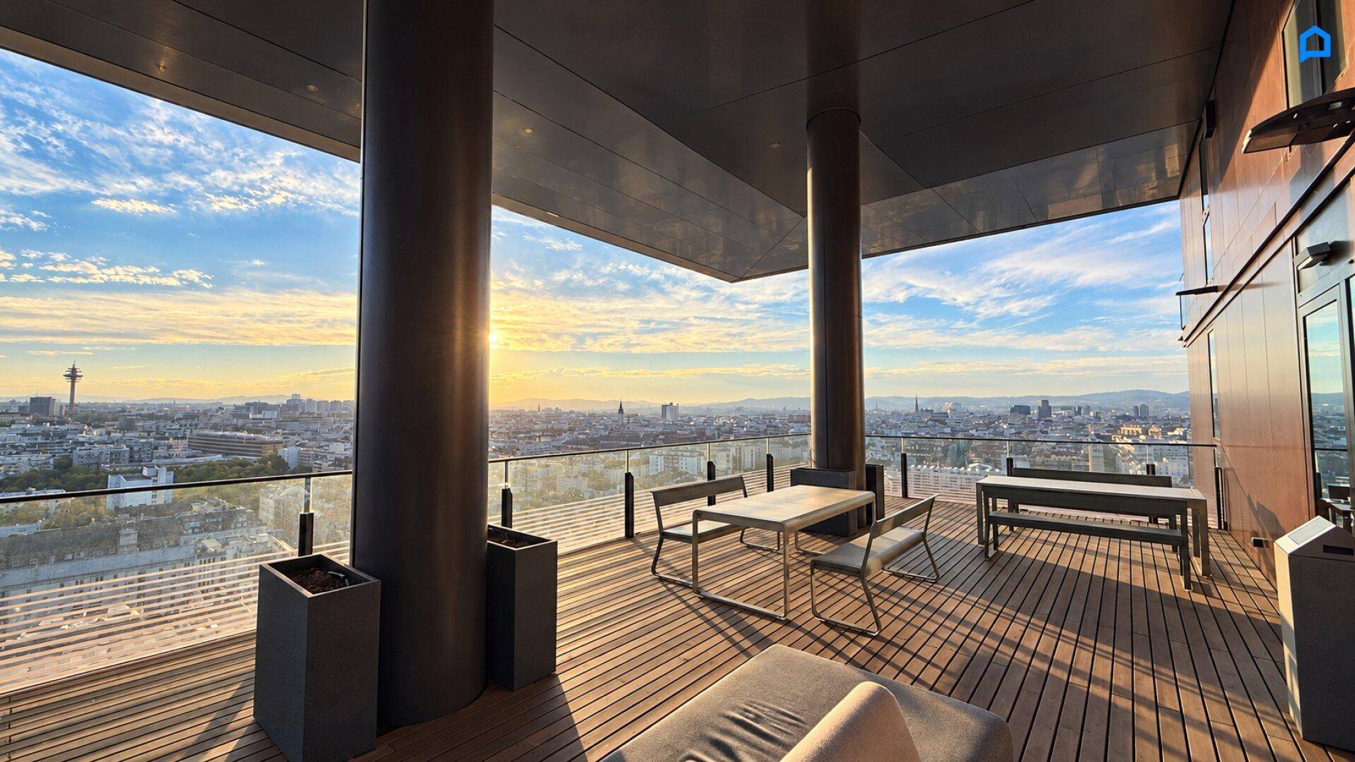 Geräumige Dachterrasse mit Holzboden, Sitzgelegenheiten und weitem Panoramablick über die Stadt.