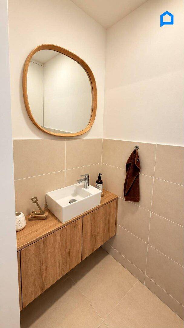 Modernes Gäste-WC mit Holzwaschtisch, Aufsatzwaschbecken und ovalem Spiegel.