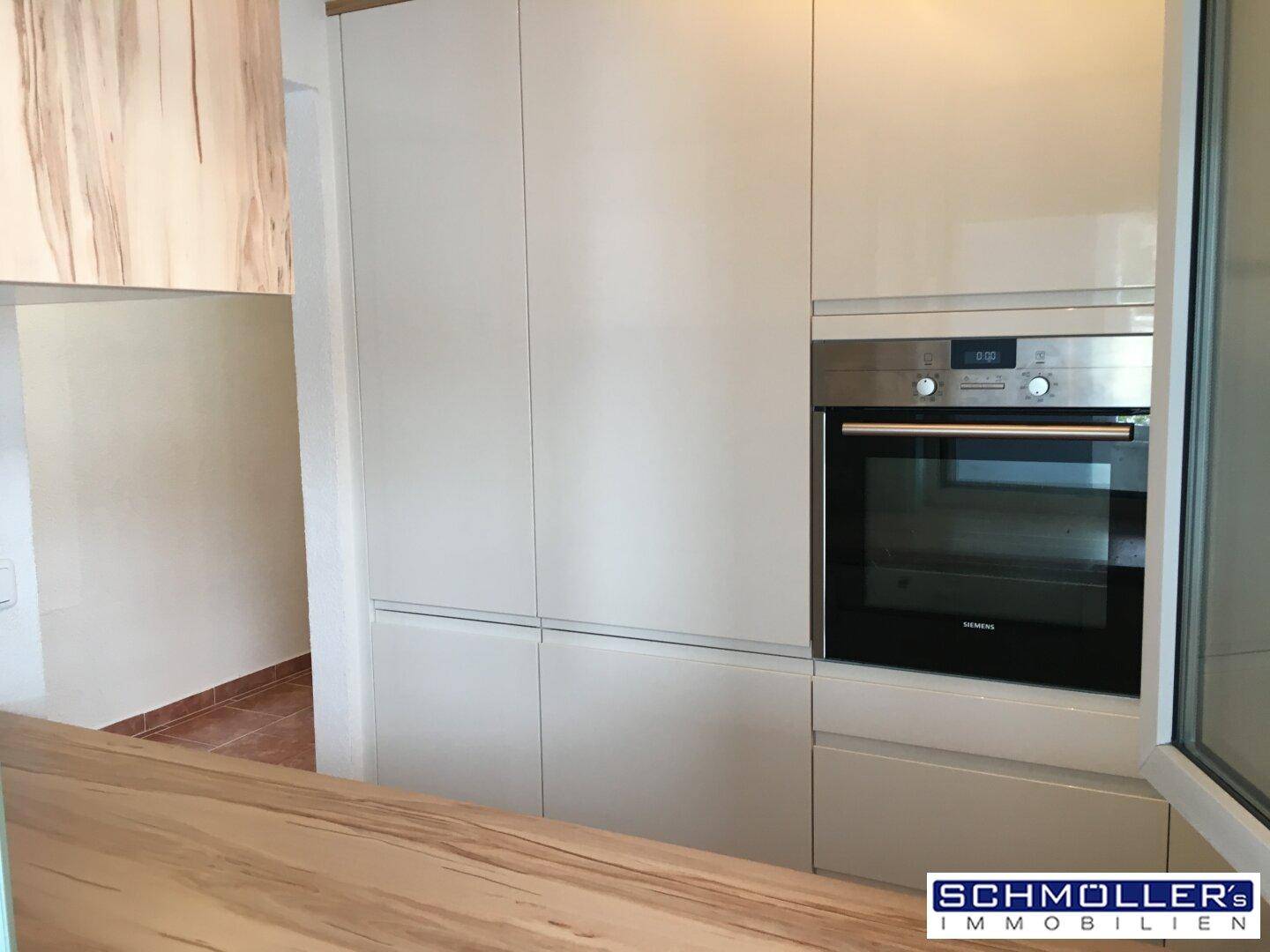 Helle Einbauküche mit modernen Geräten und Holzdetails, die eine offene Gestaltung andeutet.