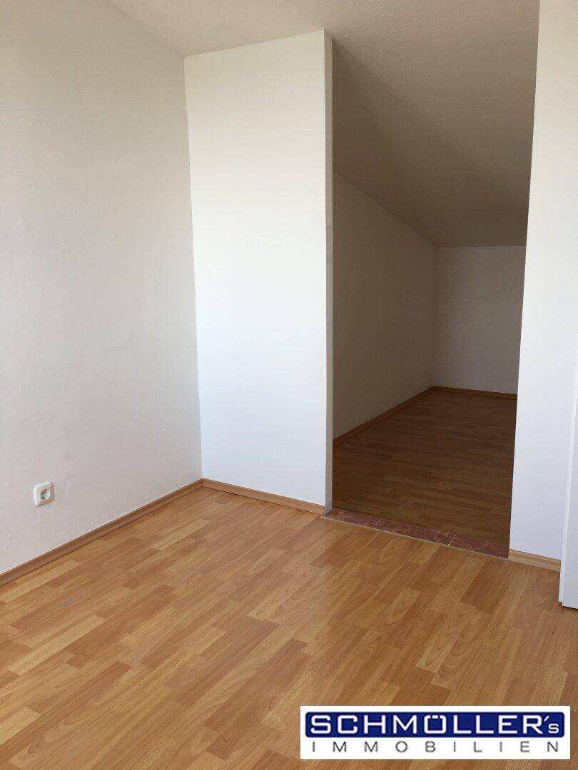 Helles Zimmer mit Laminatboden und Dachschräge, ideal als Schlaf- oder Arbeitsbereich.