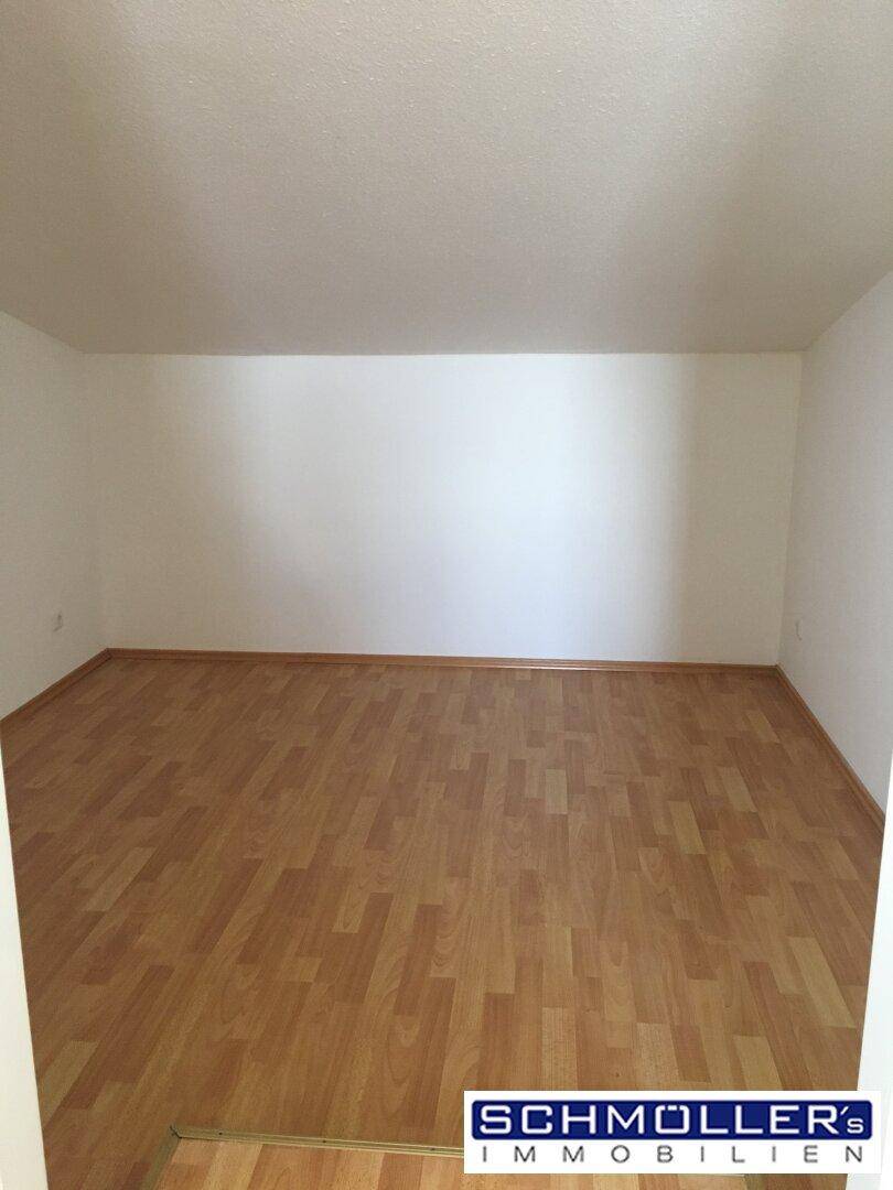 Geräumiges, helles Zimmer mit Laminatboden und weißen Wänden, vielseitig nutzbar.