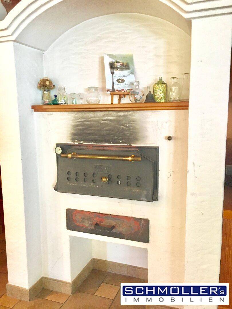 Traditioneller Backofen oder Kamin mit rustikaler Oberfläche und Holzregal für Dekorationen.