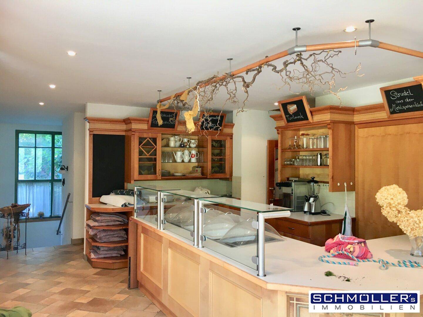 Theke mit Glasvitrinen und Holzschränken, ideal für den Verkauf von Backwaren oder Speisen.