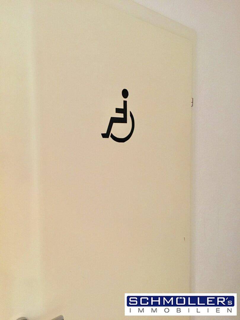 Tür mit Rollstuhlsymbol, das die Barrierefreiheit des Gebäudes kennzeichnet.