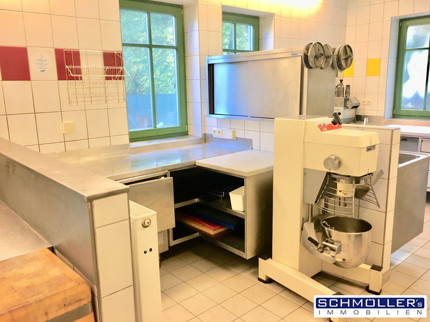 Bereich einer Großküche mit professioneller Küchenmaschine und weiteren Edelstahl-Arbeitsflächen.