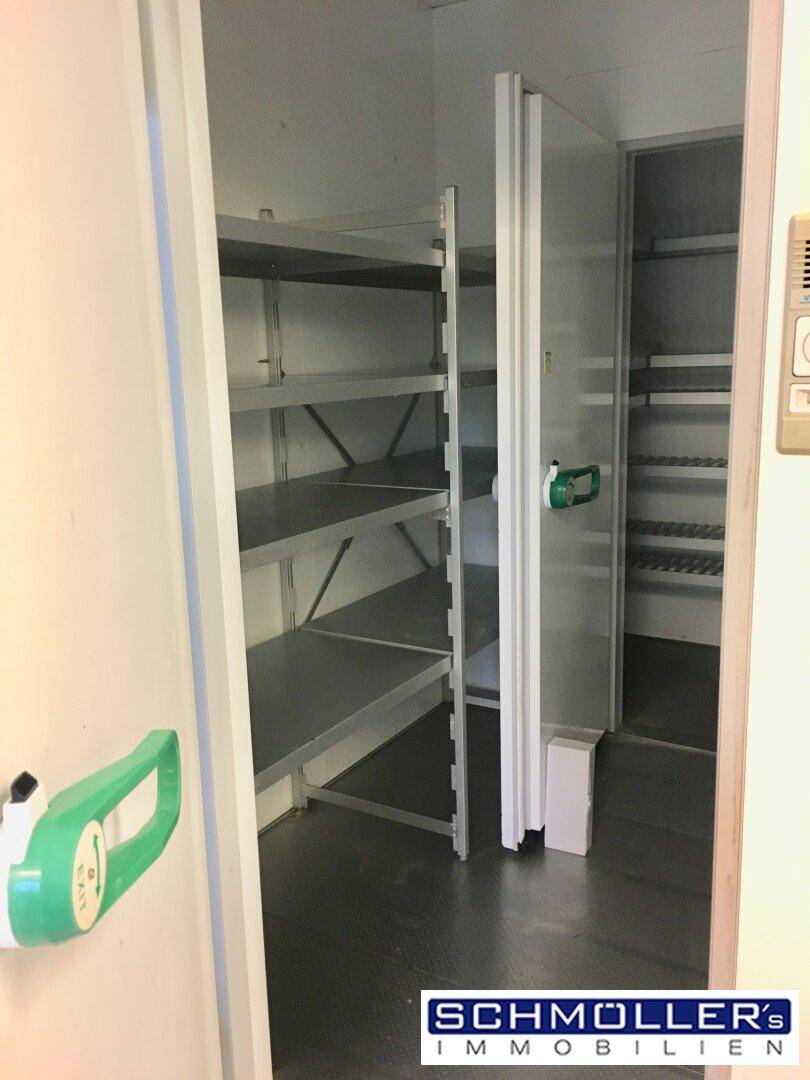 Begehbarer Kühlraum mit Metallregalen zur Lagerung von Lebensmitteln oder anderen Gütern.