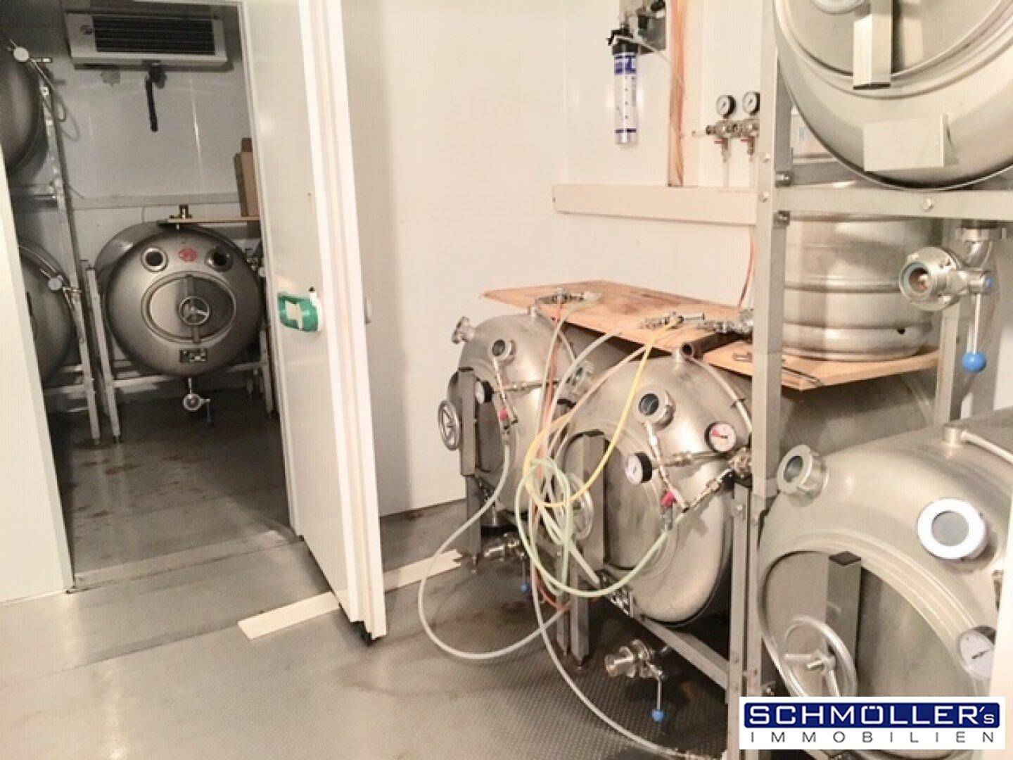 Große Edelstahltanks in einem Lagerraum, wahrscheinlich für die Bierherstellung oder -lagerung.