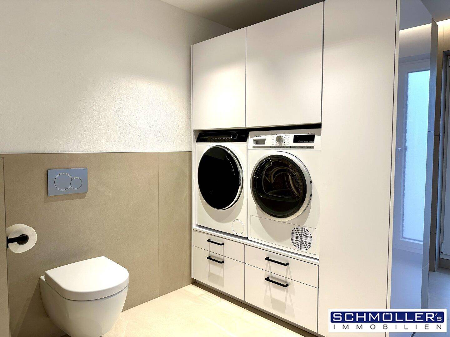 Praktischer Hauswirtschaftsraum mit Waschmaschine, Trockner und Wand-WC.