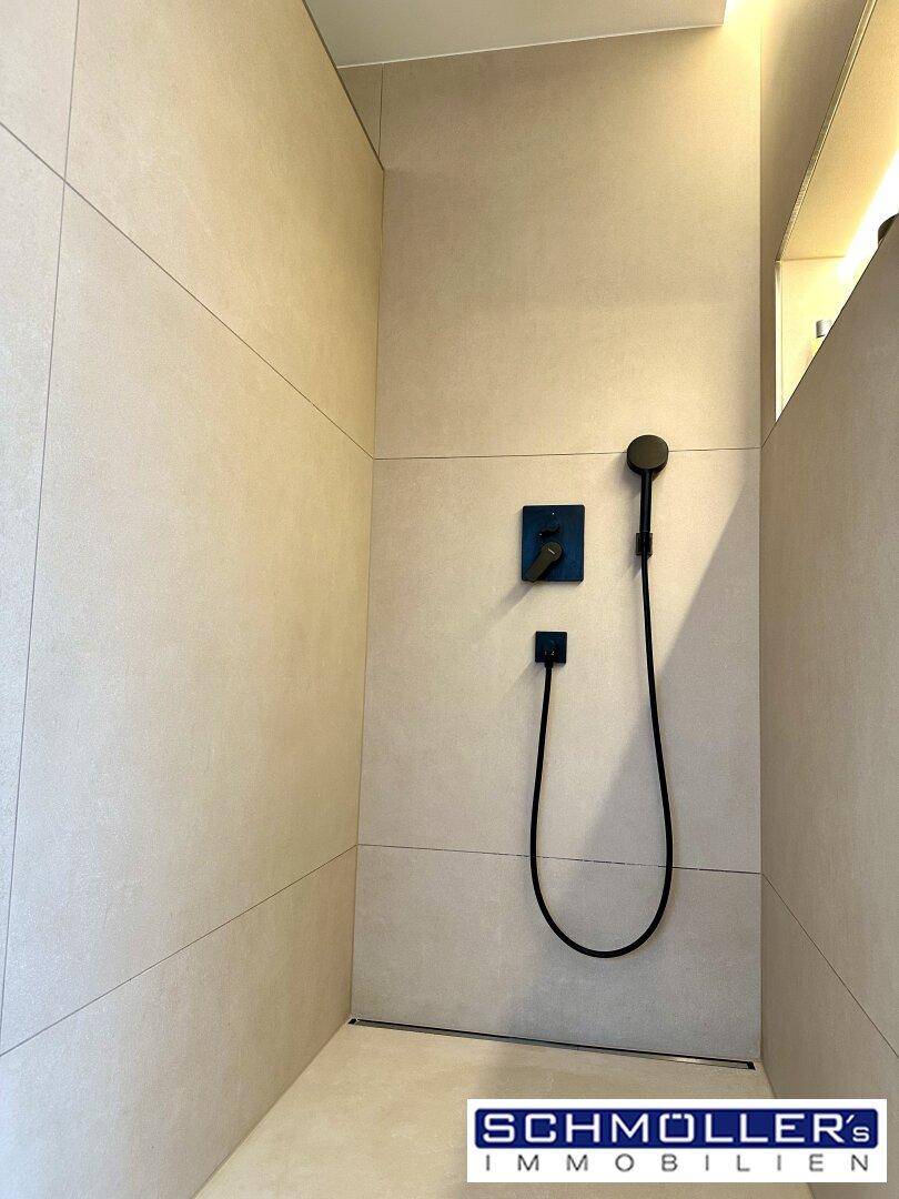 Ebenerdige Dusche mit minimalistischem Design und dunklen Armaturen.