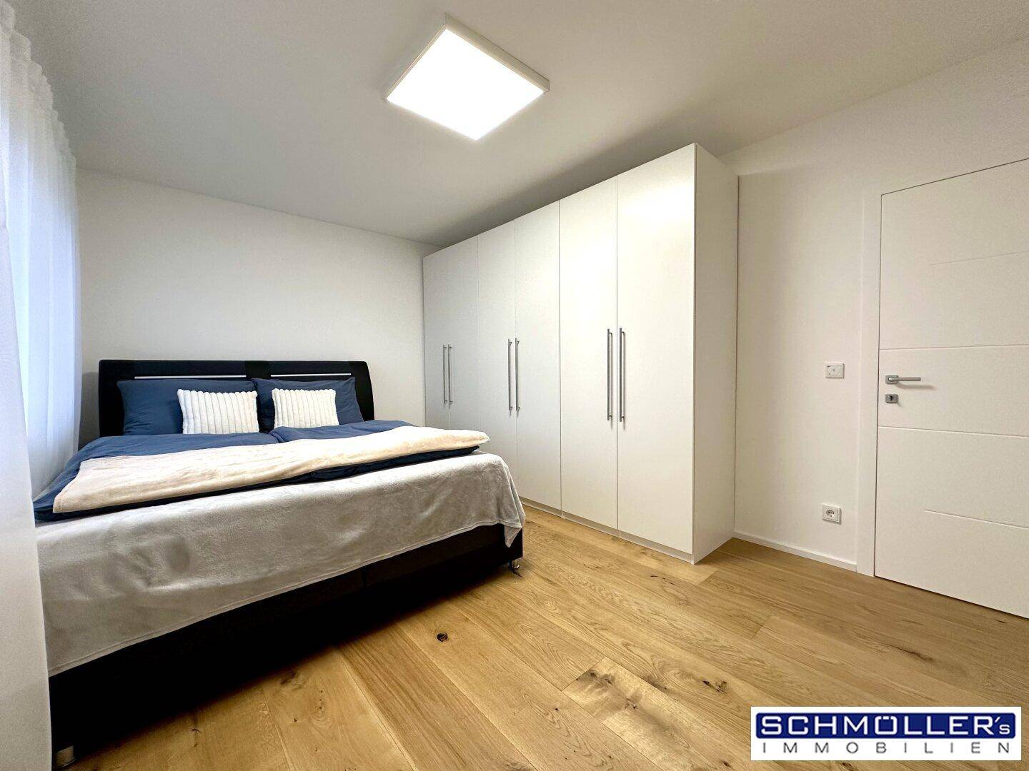 Gemütliches Schlafzimmer mit Doppelbett, Holzboden und weißen Einbauschränken.
