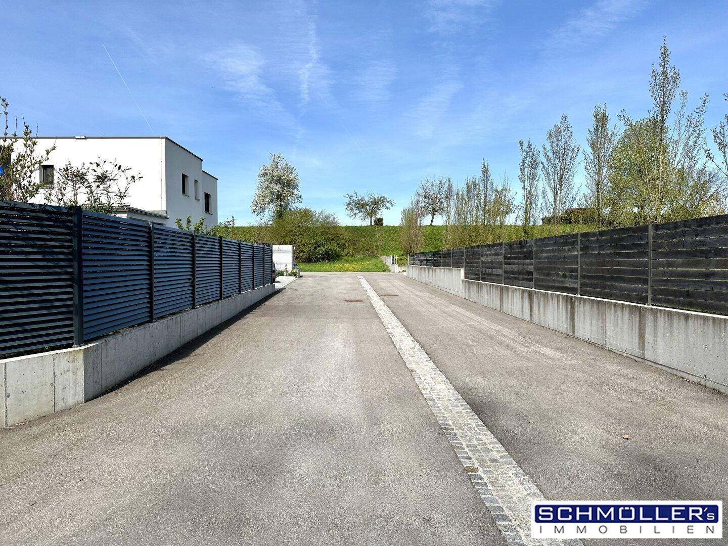 Zufahrtsweg zum Grundstück mit moderner Zaunanlage und ländlicher Umgebung.