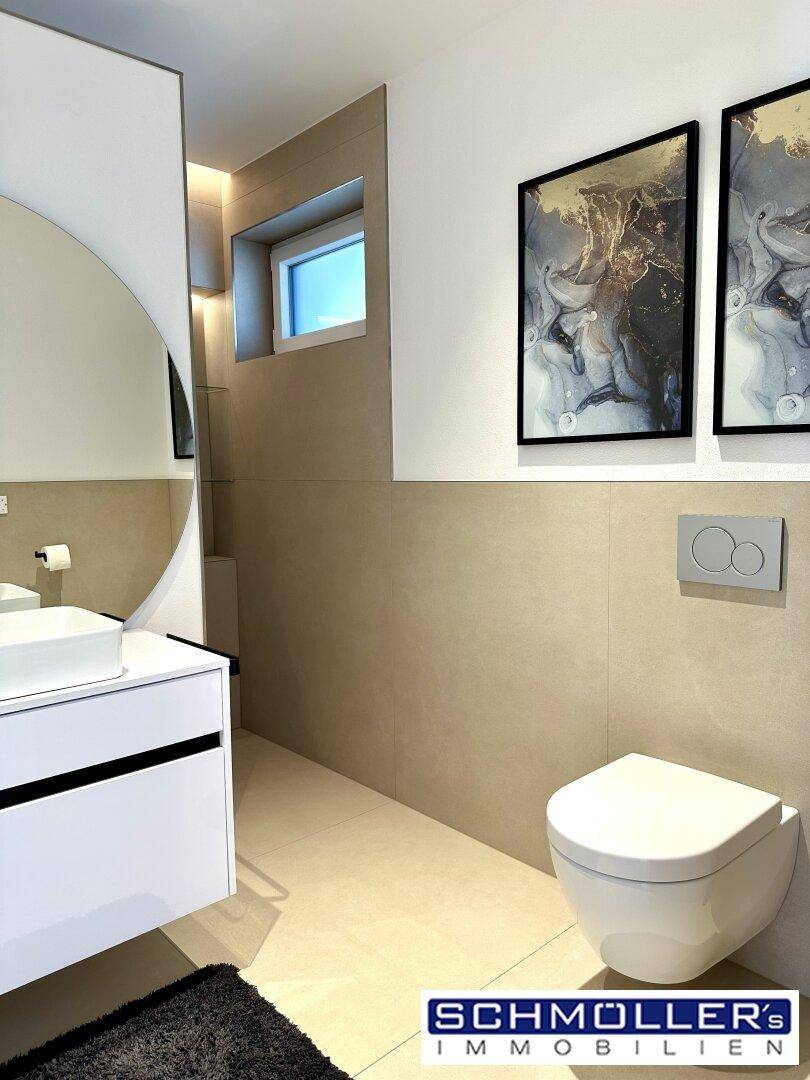 Modernes Gäste-WC mit Wand-WC, eleganten Fliesen und kleinem Fenster.