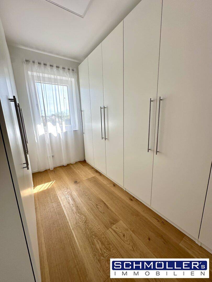 Begehbarer Kleiderschrank mit Einbauschränken und Fenster für natürliches Licht.