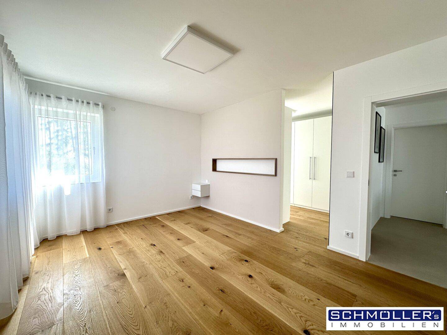 Geräumiges Schlafzimmer mit hellem Holzboden und viel Tageslicht.