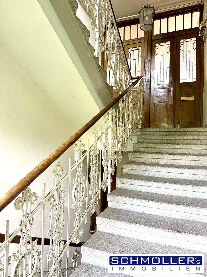 Elegantes Treppenhaus mit kunstvollem Geländer und Holzhandlauf in einem Altbau.
