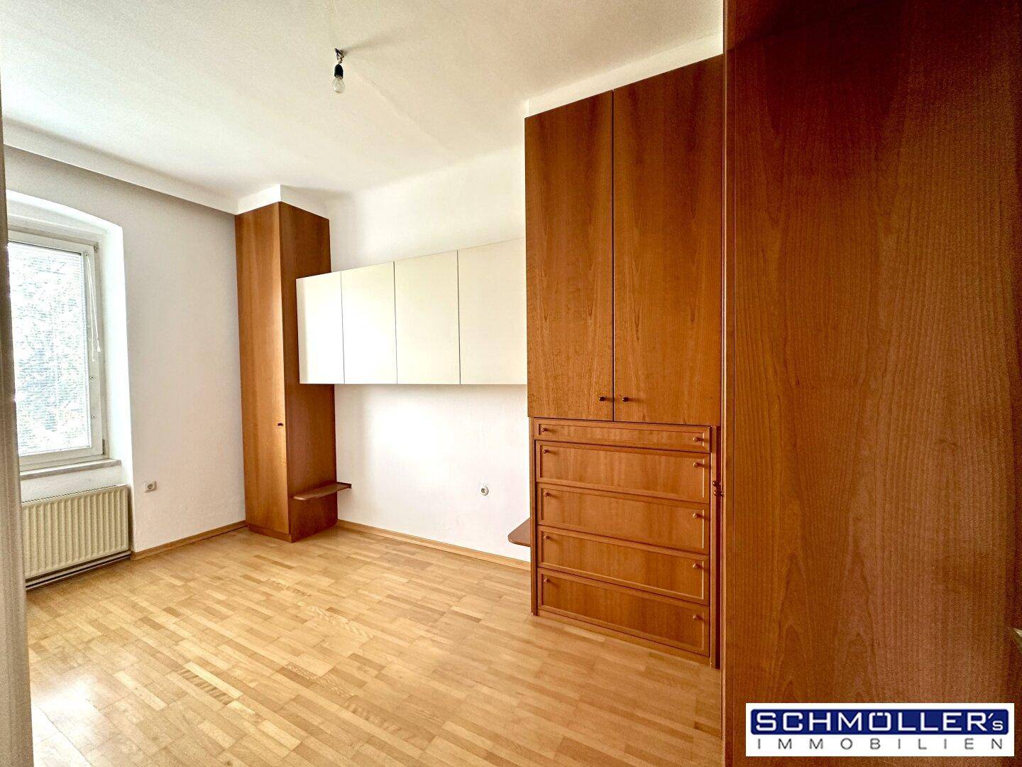 Schlafzimmer mit Holzboden und Einbauschränken, bietet viel Stauraum und Helligkeit.