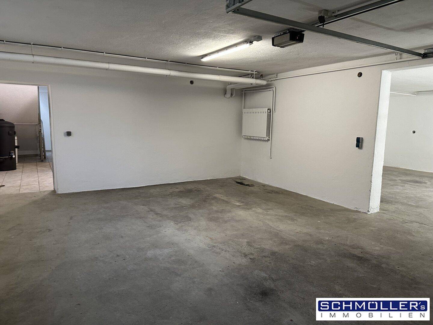 Großer Kellerraum oder Garage mit Betonboden und weiß gestrichenen Wänden, mit Elektroverteilung.