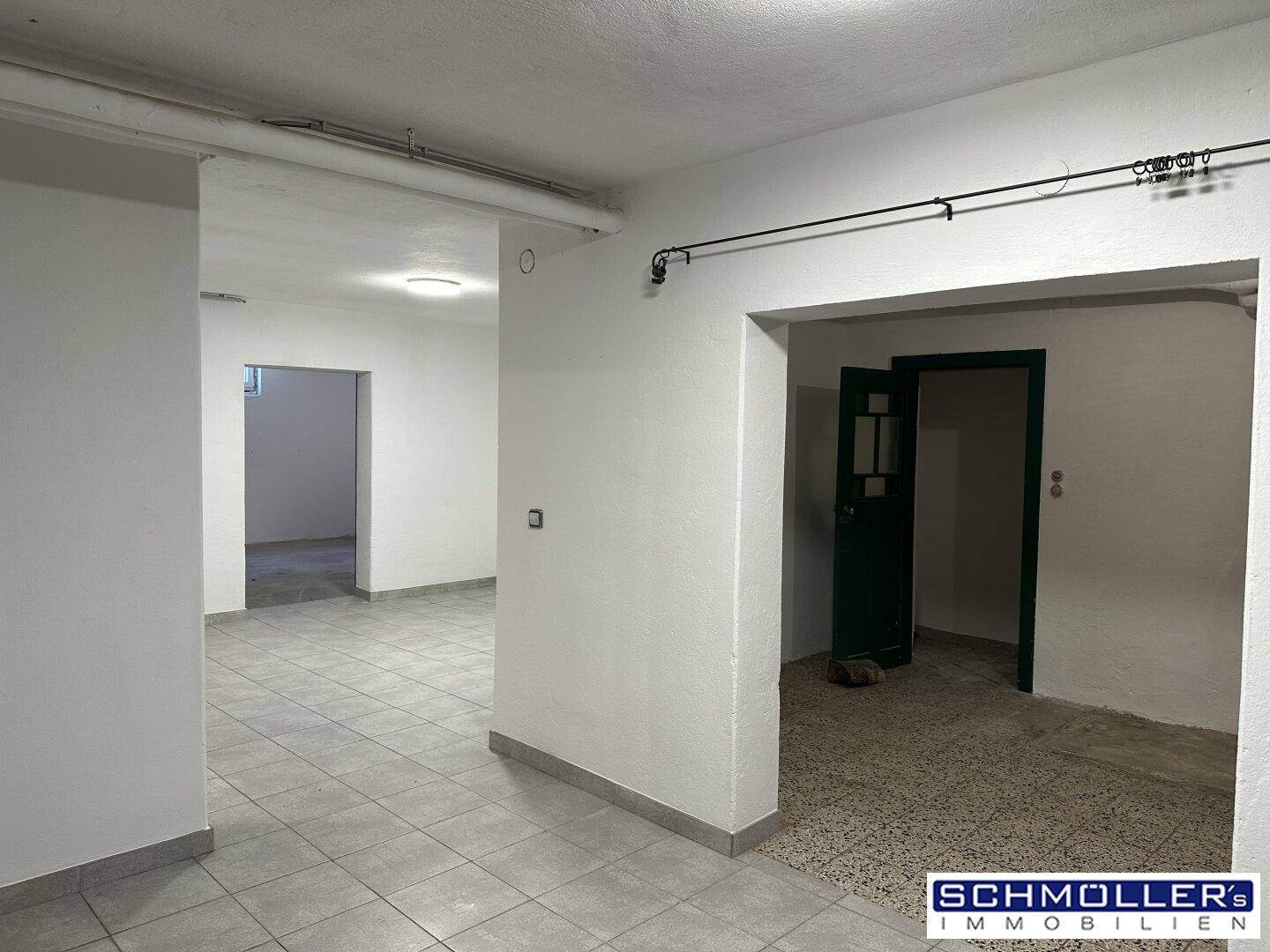 Geräumiger Kellerbereich mit gefliestem Boden und mehreren Zugängen zu weiteren Räumen.