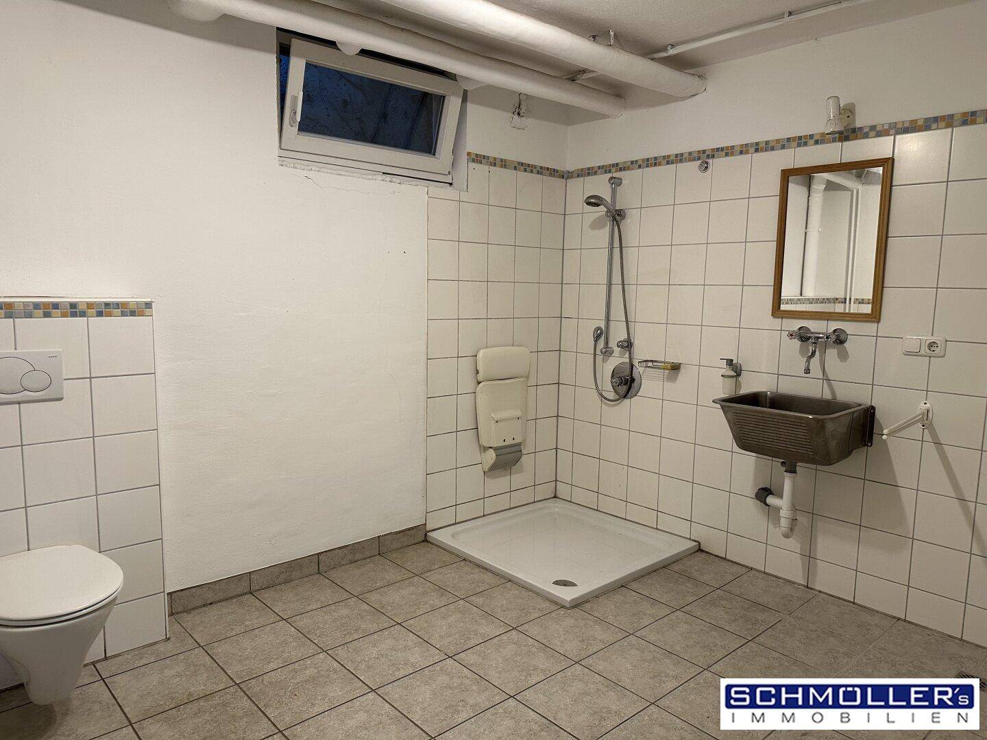 Funktionales Badezimmer im Keller mit Dusche, WC und Waschbecken, einfach gefliest.